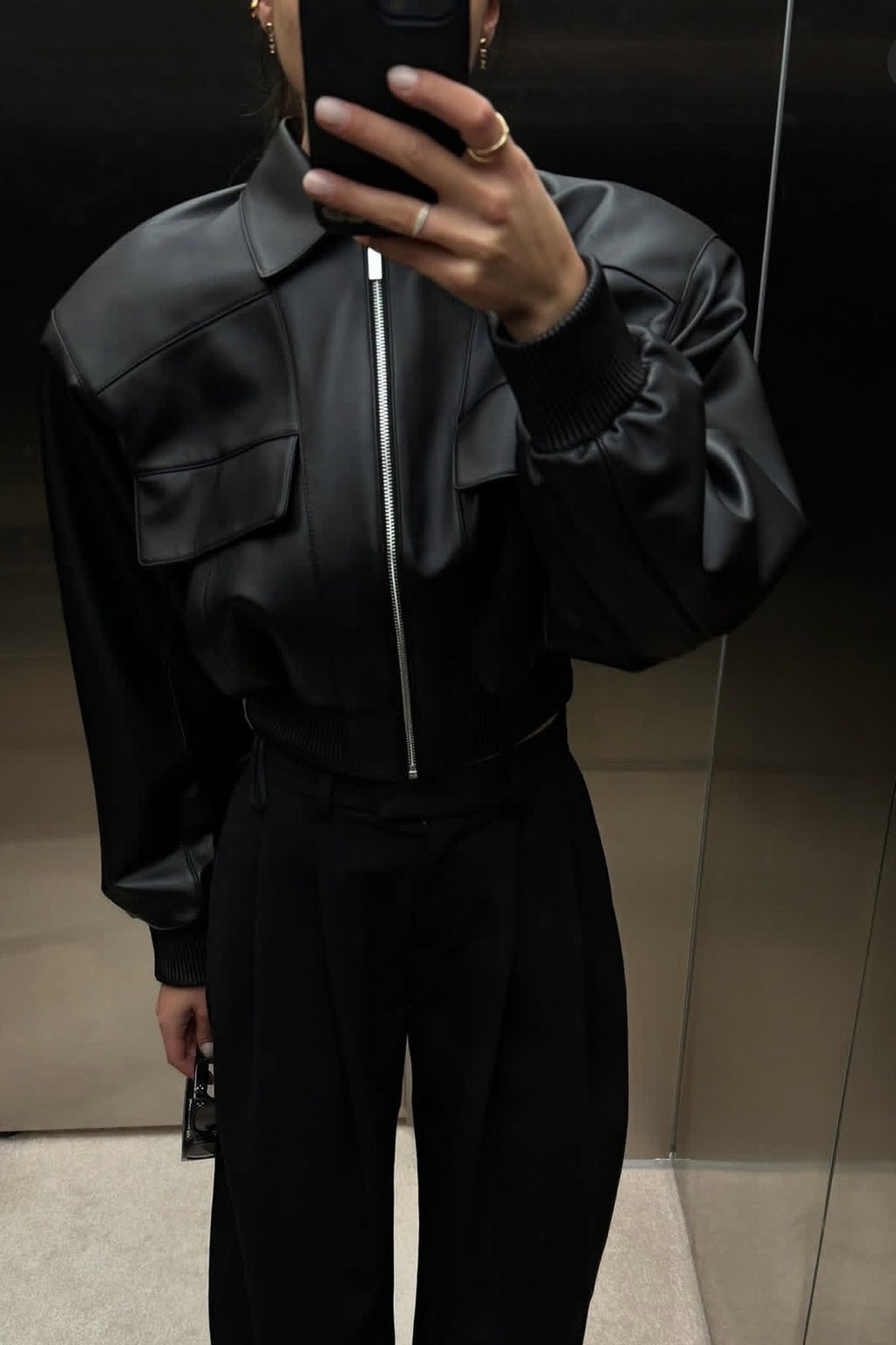 Black leather aviator jacket on model with zip front and flap pockets