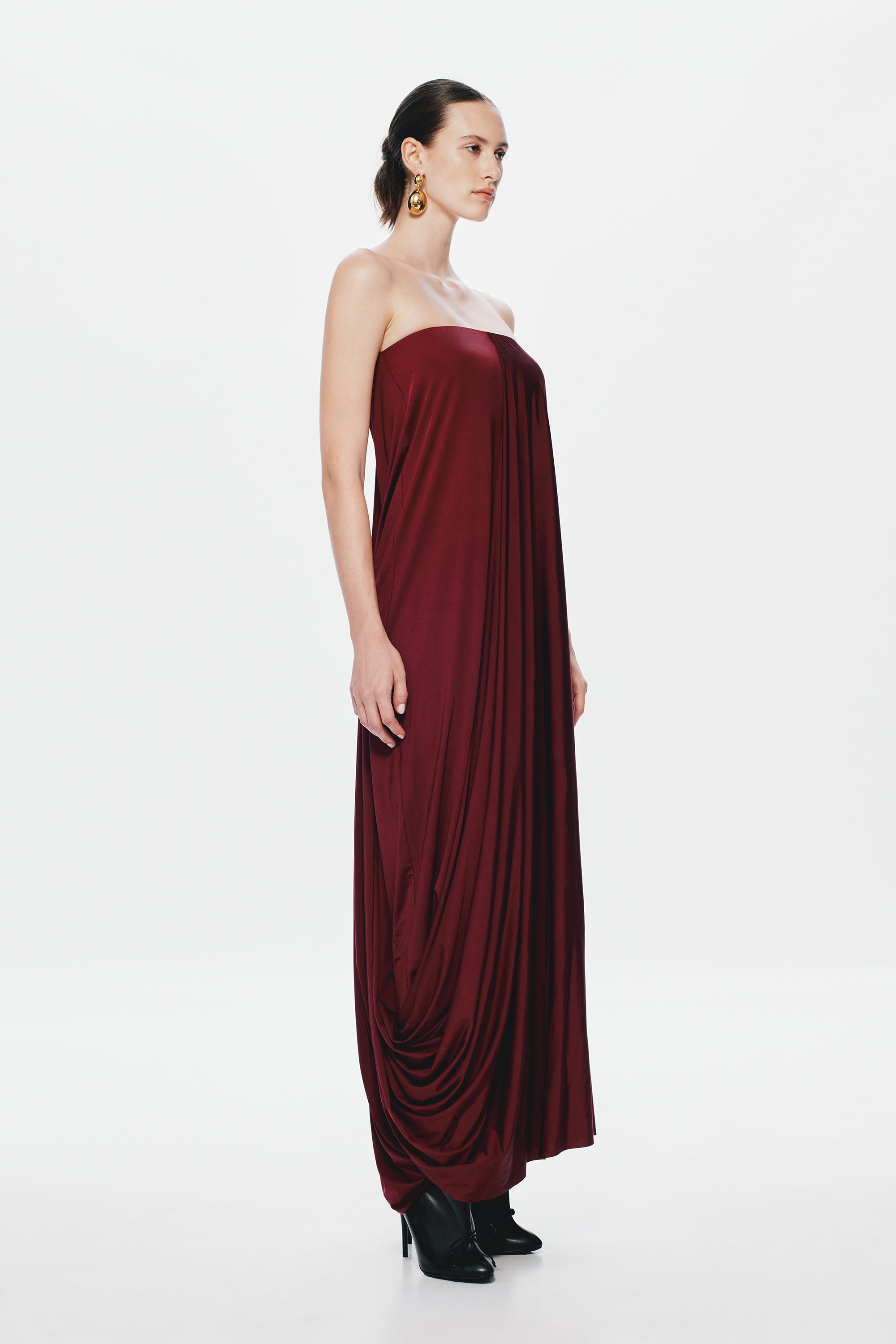 Burgundy strapless jersey maxi dress with gathered folds and draped cowl-like skirt