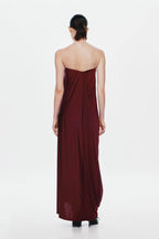 Burgundy strapless jersey maxi dress with cross-back paneling and draped skirt