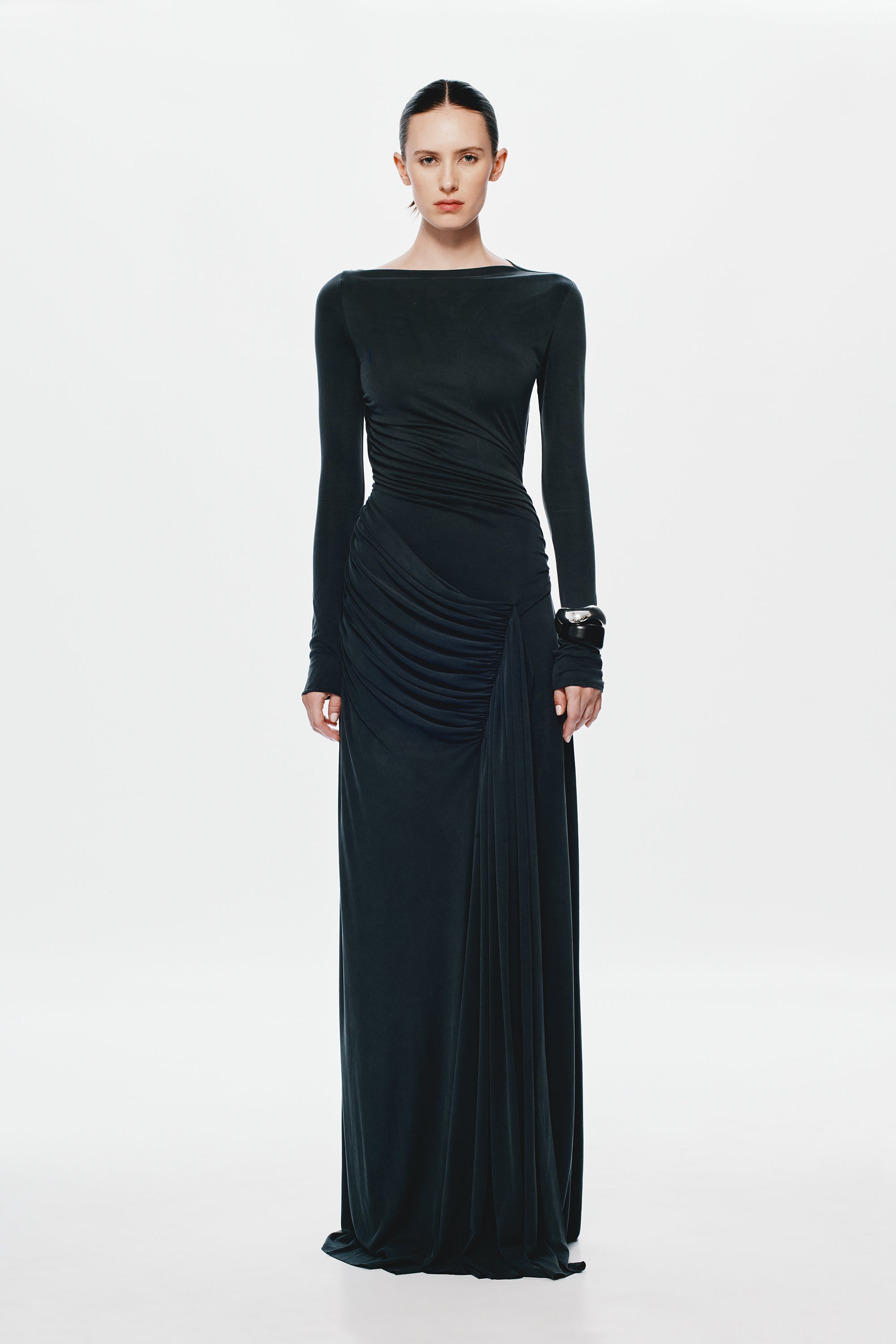 Black long-sleeve maxi dress with ruched waist, diagonal drape, and gathered skirt