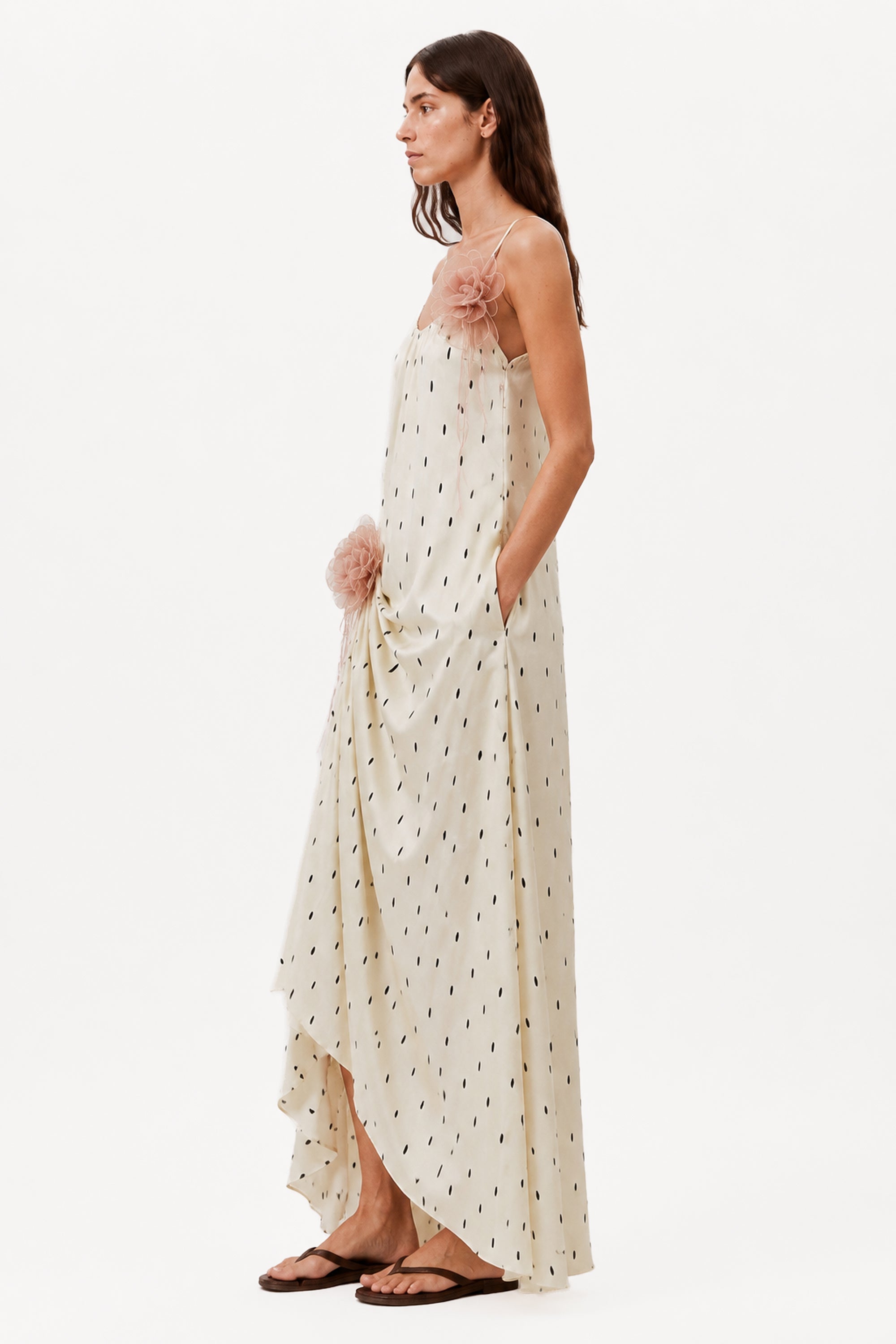 Ivory draped maxi dress with spaghetti straps, small dot print, and pink rosette detail