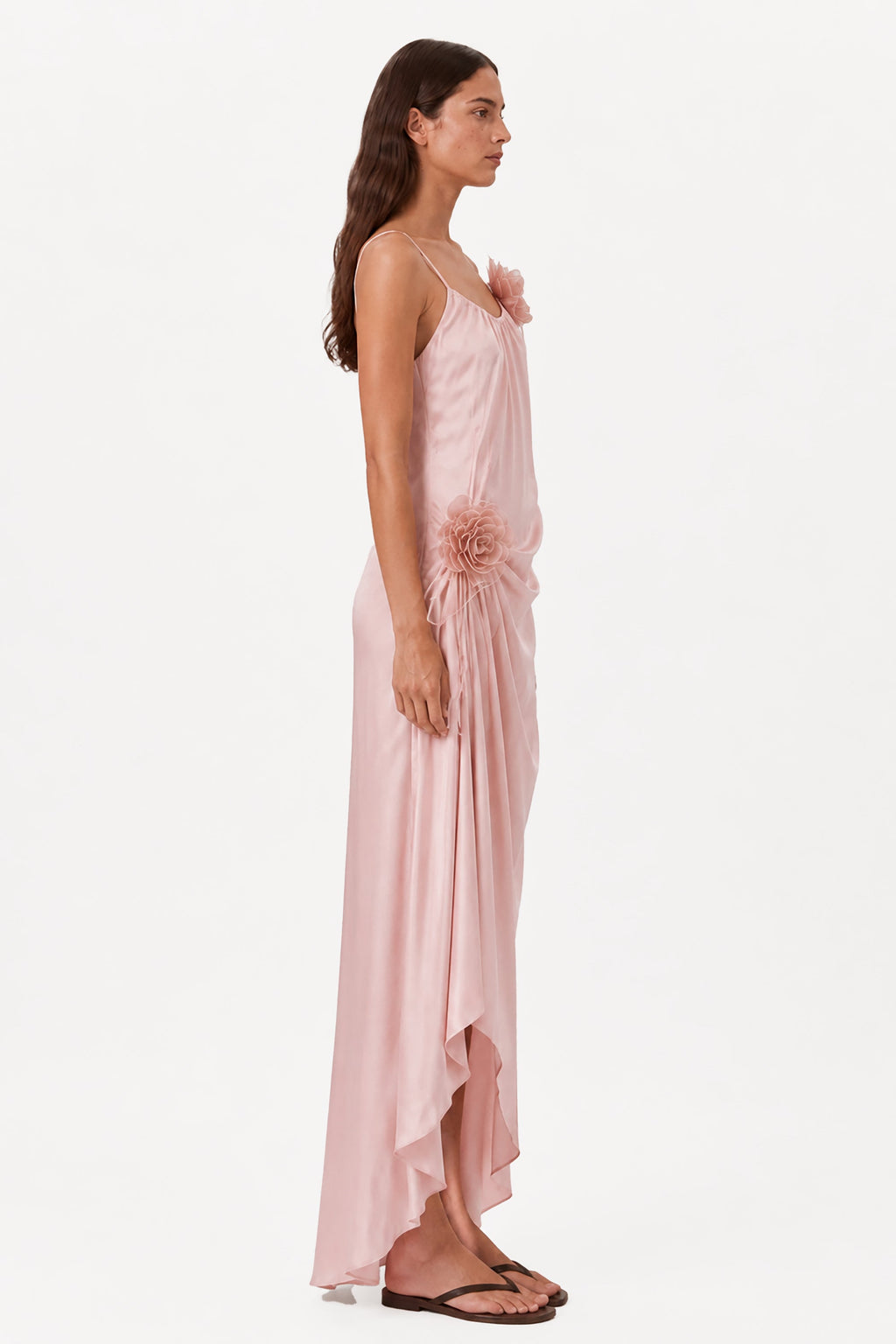 Blush pink sleeveless maxi dress with rosette detail and flowing asymmetrical skirt