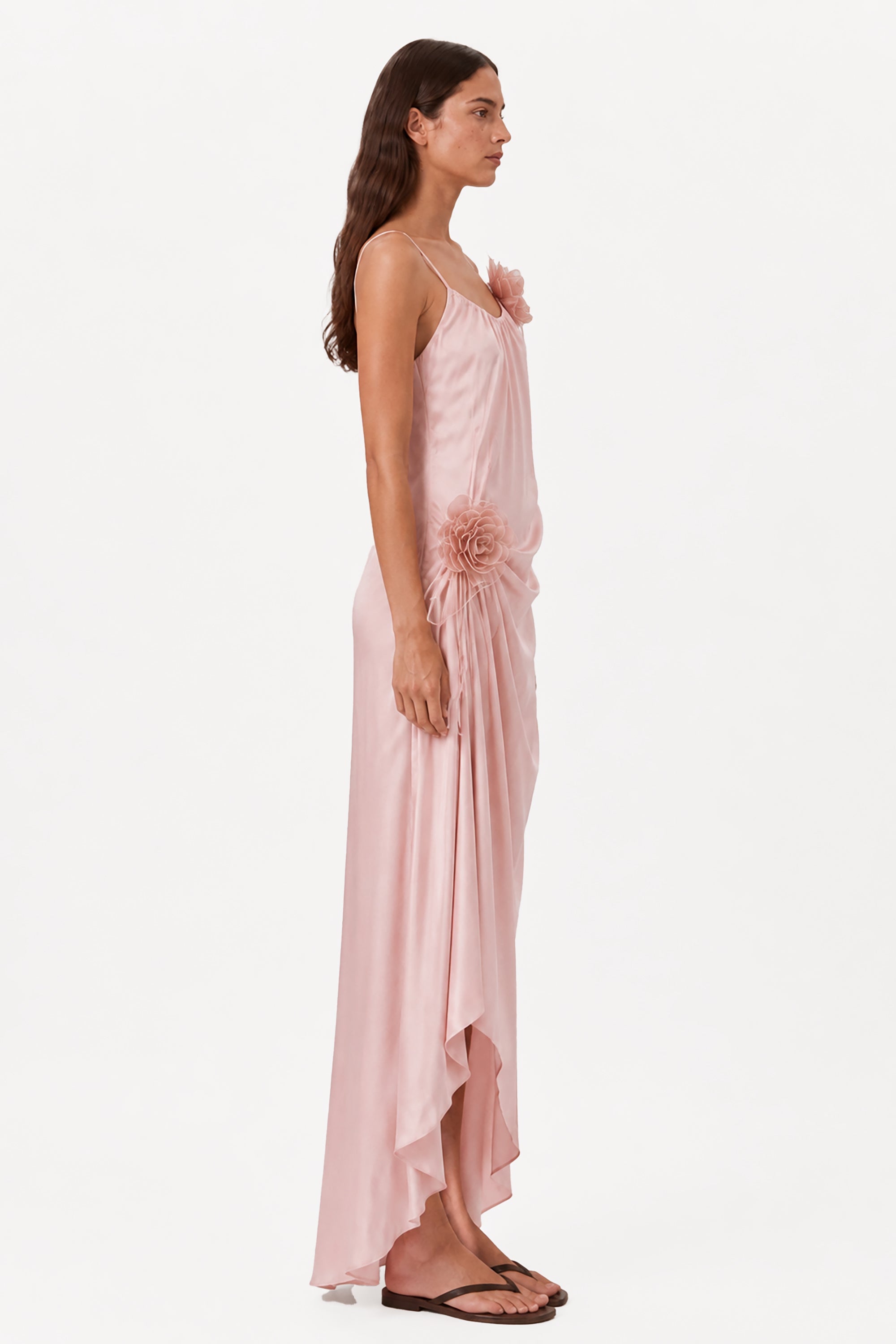 Blush pink sleeveless maxi dress with rosette detail and flowing asymmetrical skirt