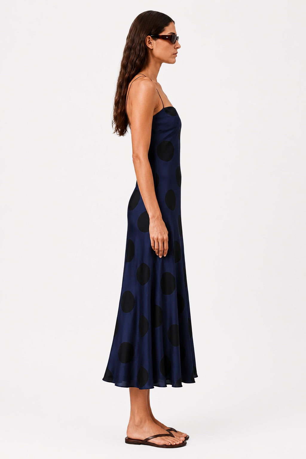 Navy polka dot bias midi dress with spaghetti straps and fitted bodice, flared skirt