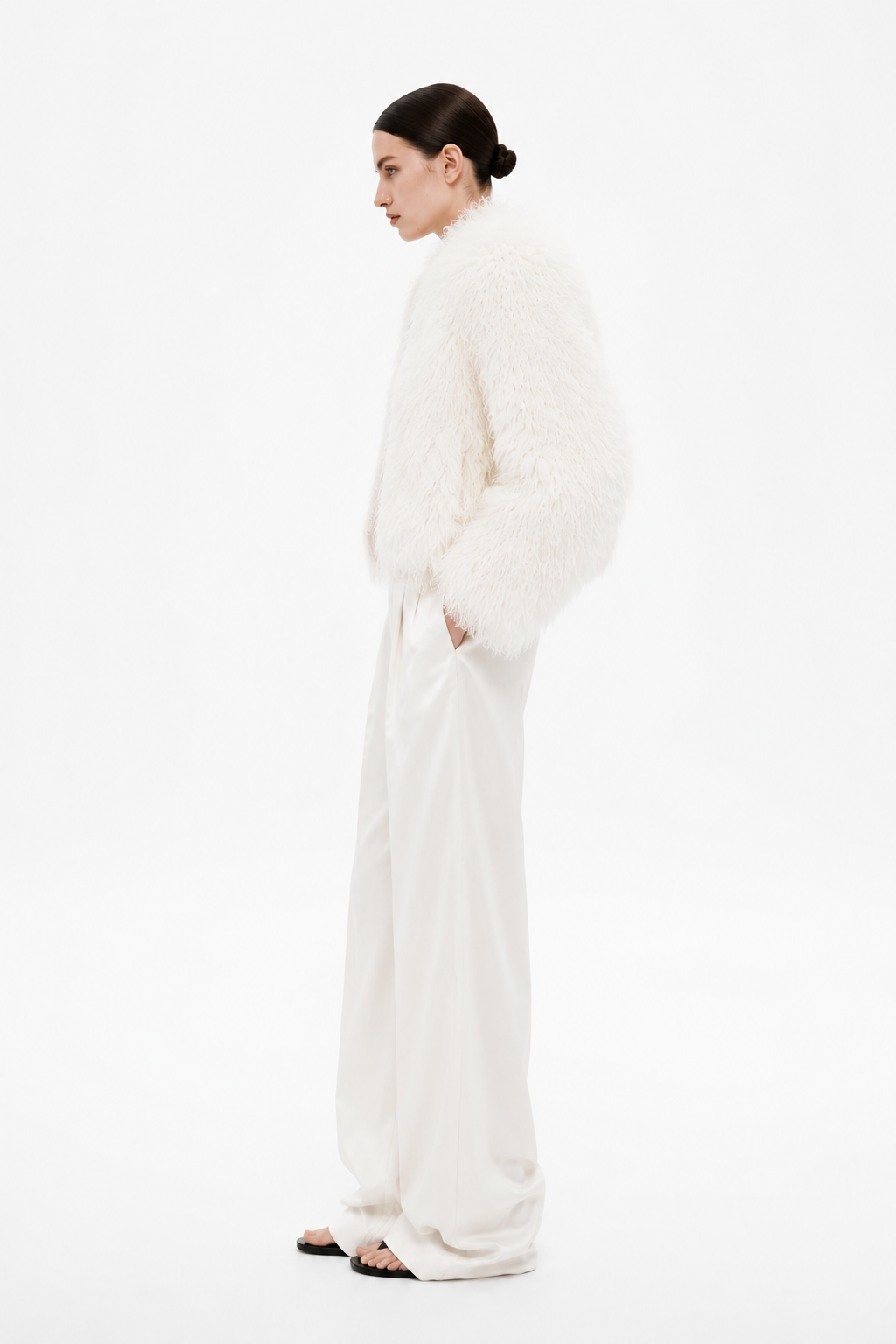 Ivory shearling coat with button front, long sleeves, paired with white trousers
