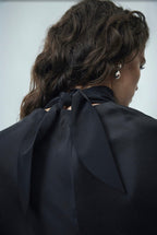 Black sheer silk blouse with high neckline and bow-like tie detail at back collar