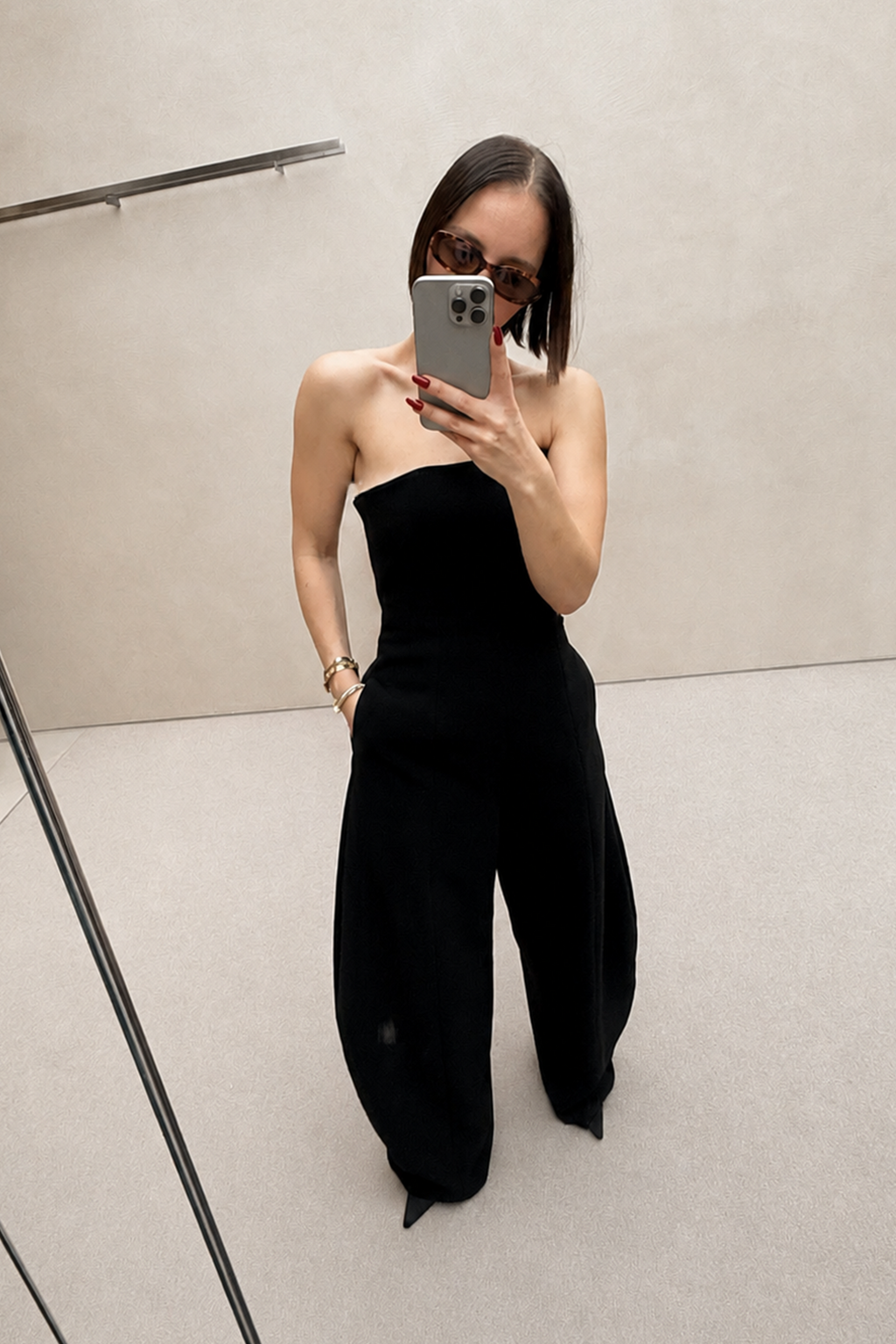 Black strapless wide-leg jumpsuit, side view with draped waist seam and flared legs