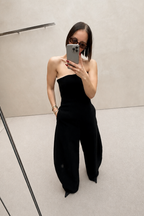 Black strapless wide-leg jumpsuit, side view with draped waist seam and flared legs