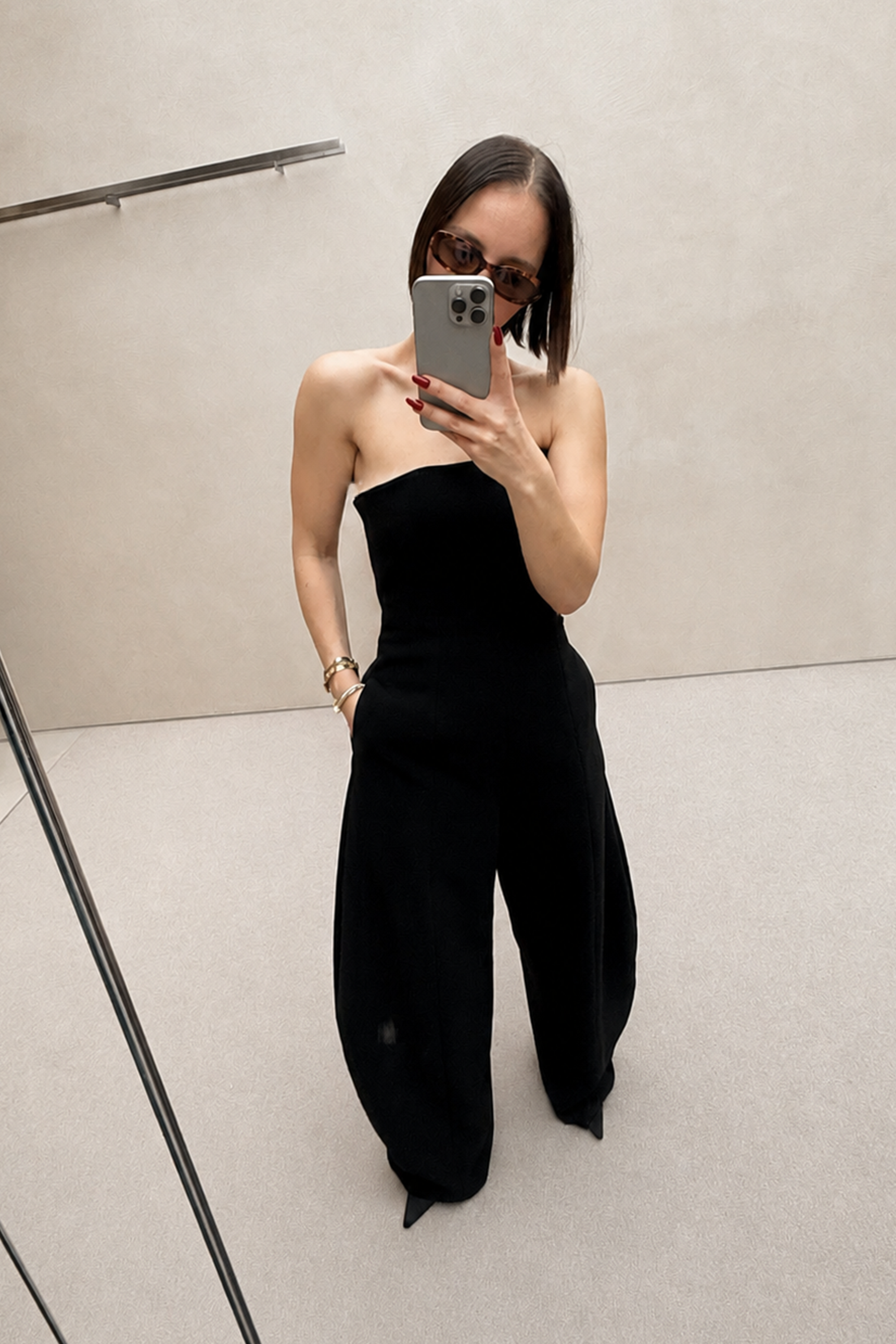 Black strapless wide-leg jumpsuit, side view with draped waist seam and flared legs