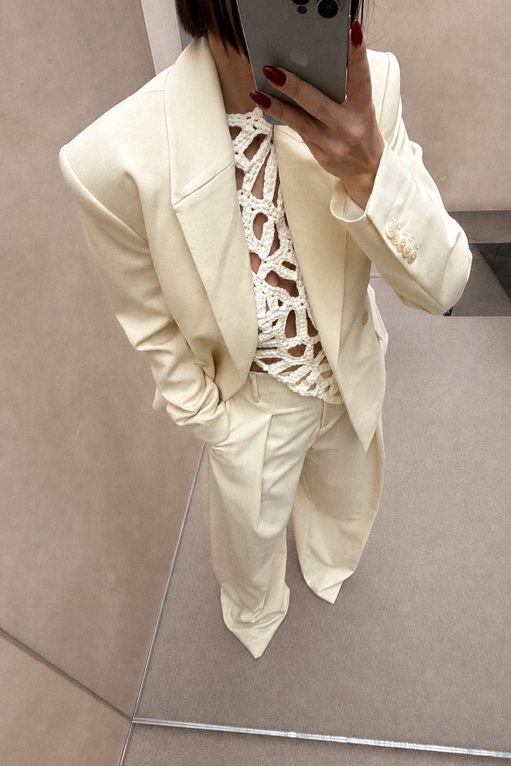 Cream blazer with notched lapels and flap pockets, long sleeves.