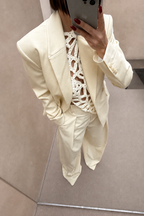 Cream blazer with notched lapels and flap pockets, long sleeves.