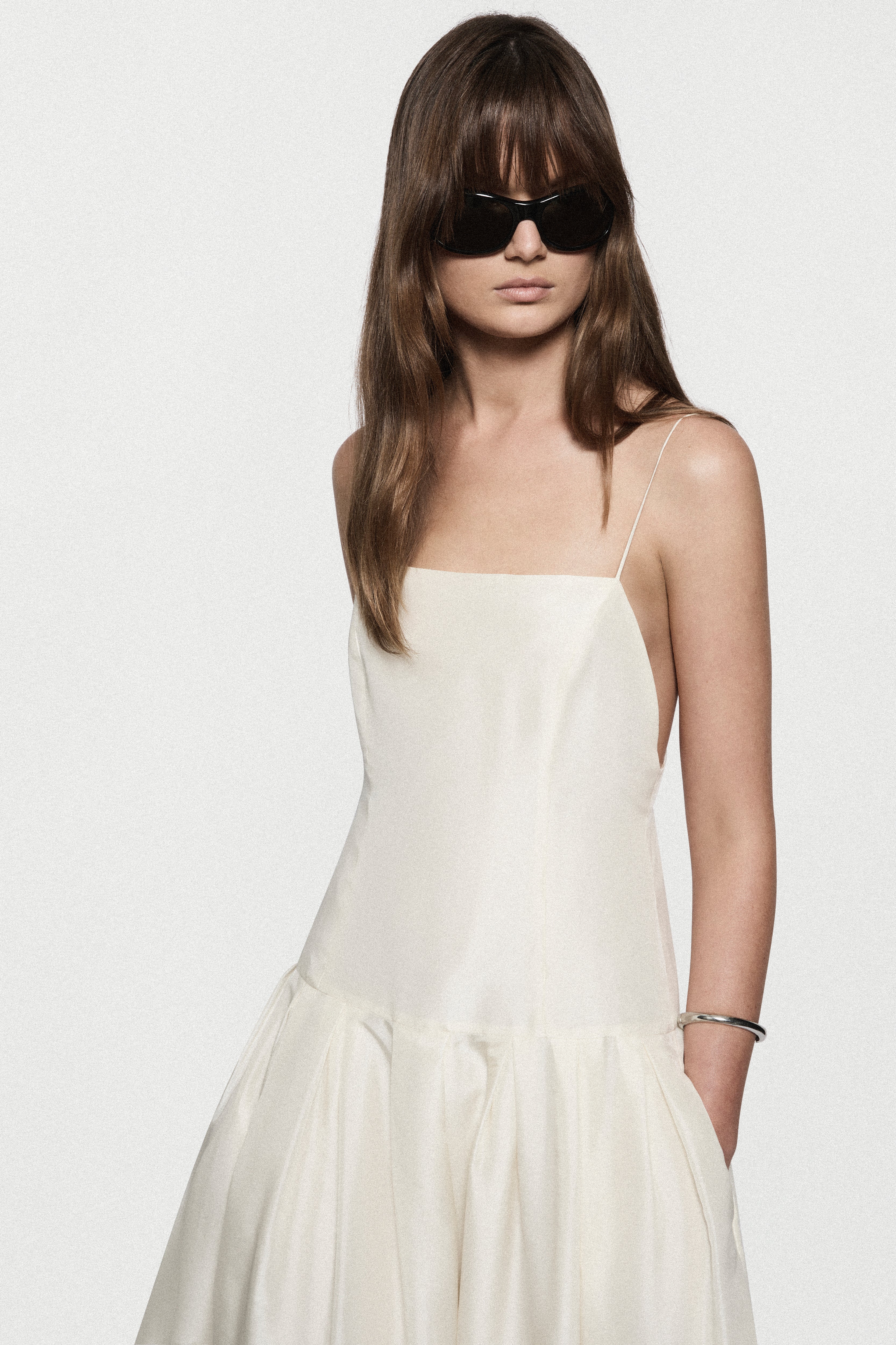 Winter white silk sundress with spaghetti straps and tiered ruffle hem, close-up front.