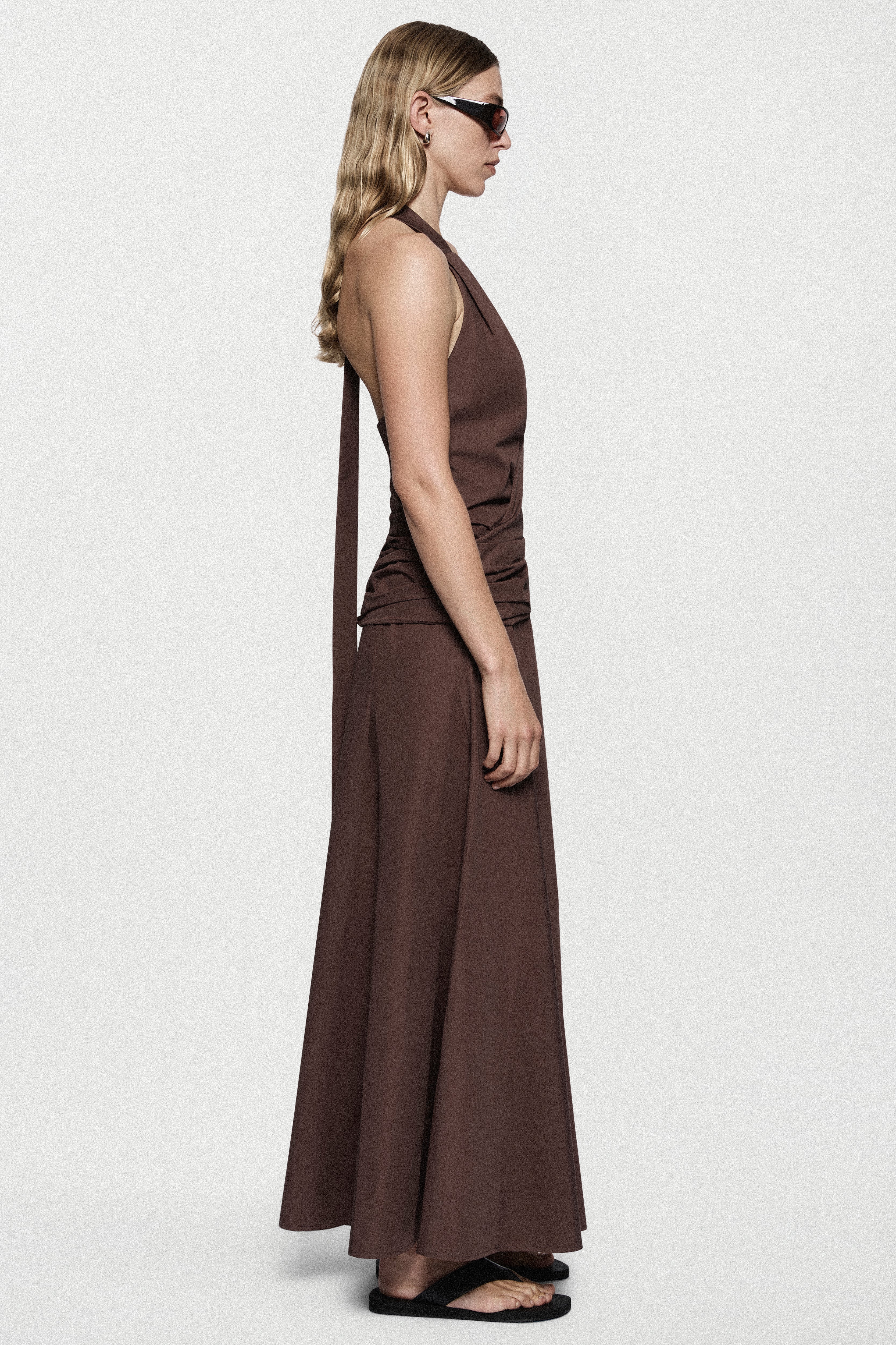 Brown cotton halter maxi dress with fitted waist and draped side silhouette