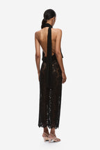 Black halter jersey top with open back, draped sash tie, and lace hem panel