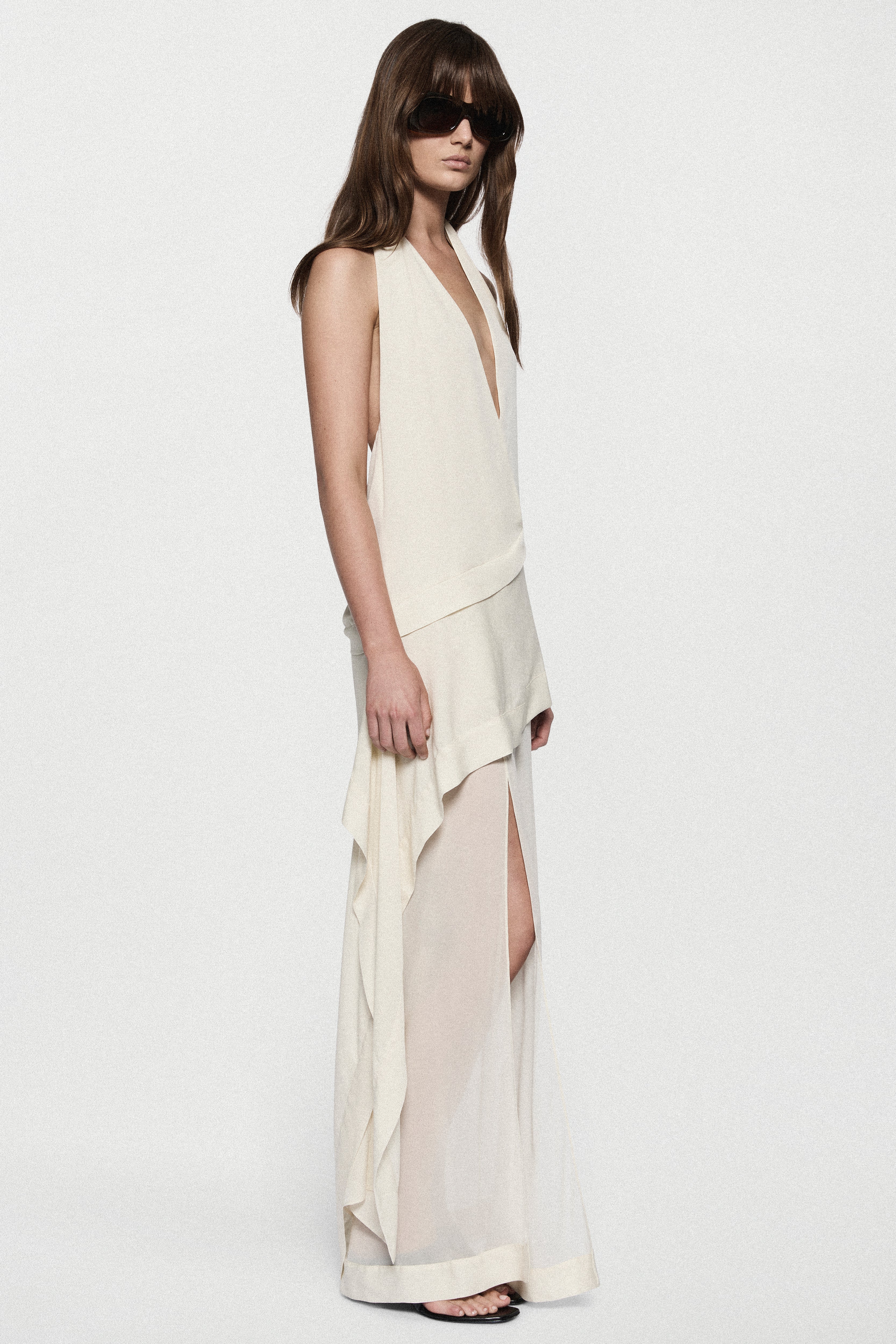 Off-white silk halter maxi dress with V neckline and side slit over layered hem
