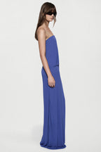 Blue strapless jersey maxi dress with straight column silhouette and side drape.