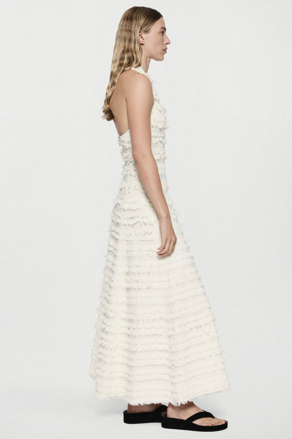 Winter white cotton fringe dress, sleeveless tiered ruffles, side profile