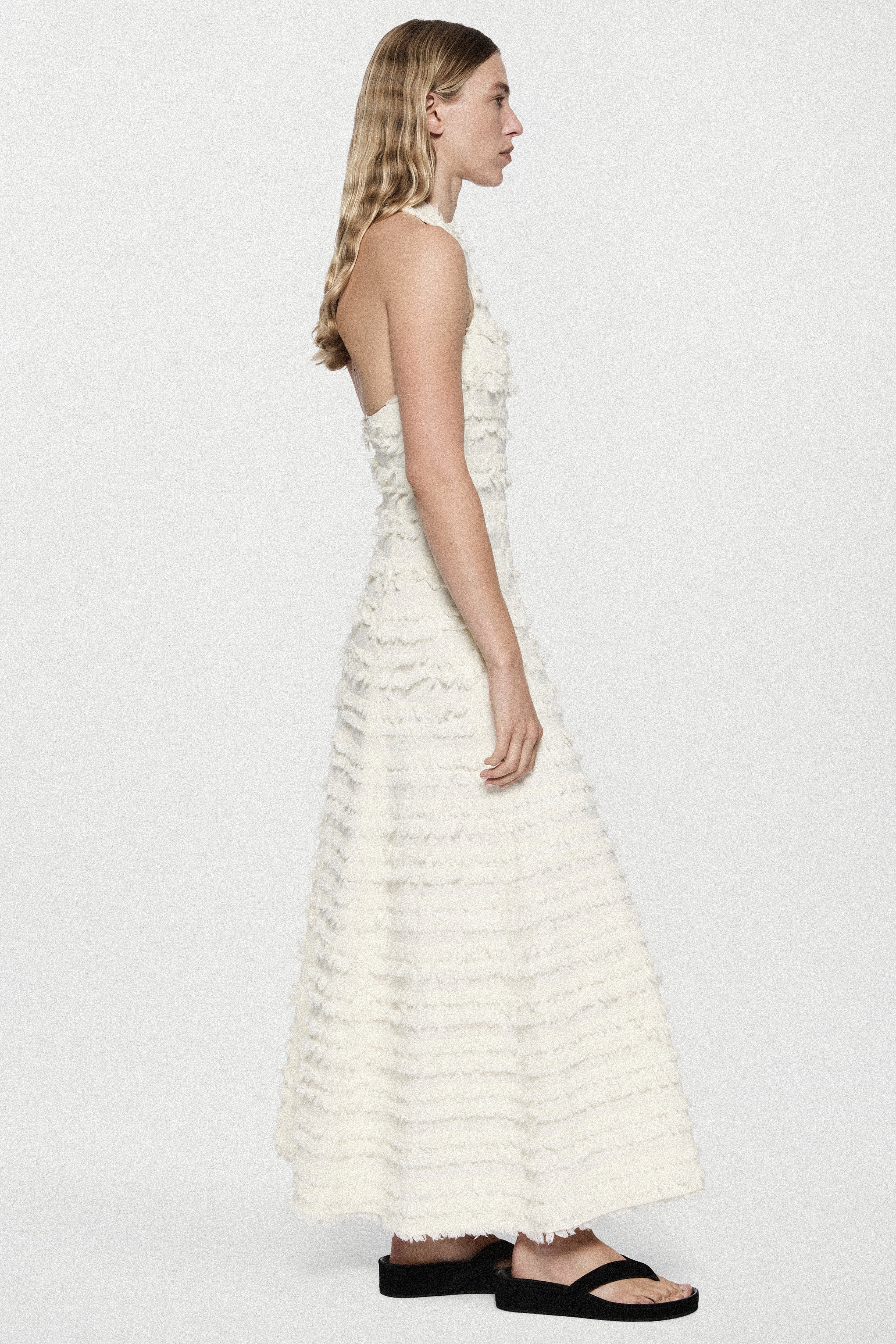Winter white cotton fringe dress, sleeveless tiered ruffles, side profile