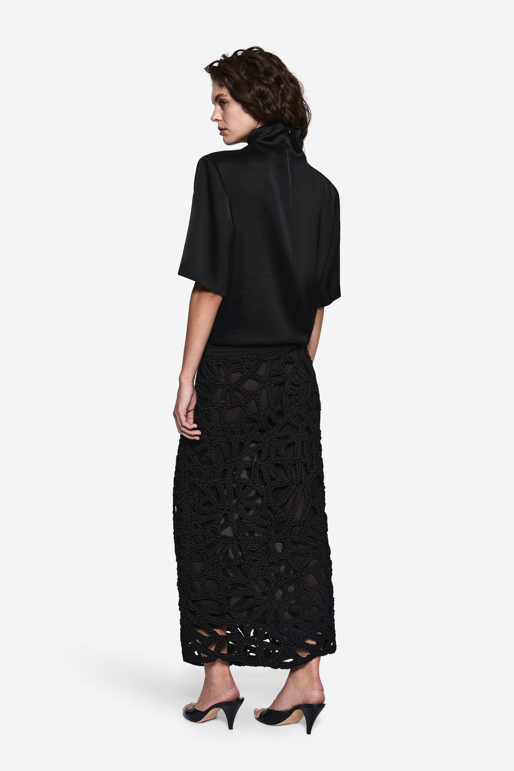 Black short-sleeve turtleneck tee with patterned black lace midi skirt, back view