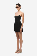 Black gathered jersey mini skirt with elastic waist and dense pleated texture.