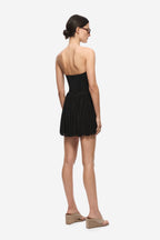 Black gathered jersey mini skirt from back view with elastic waistband pleats.