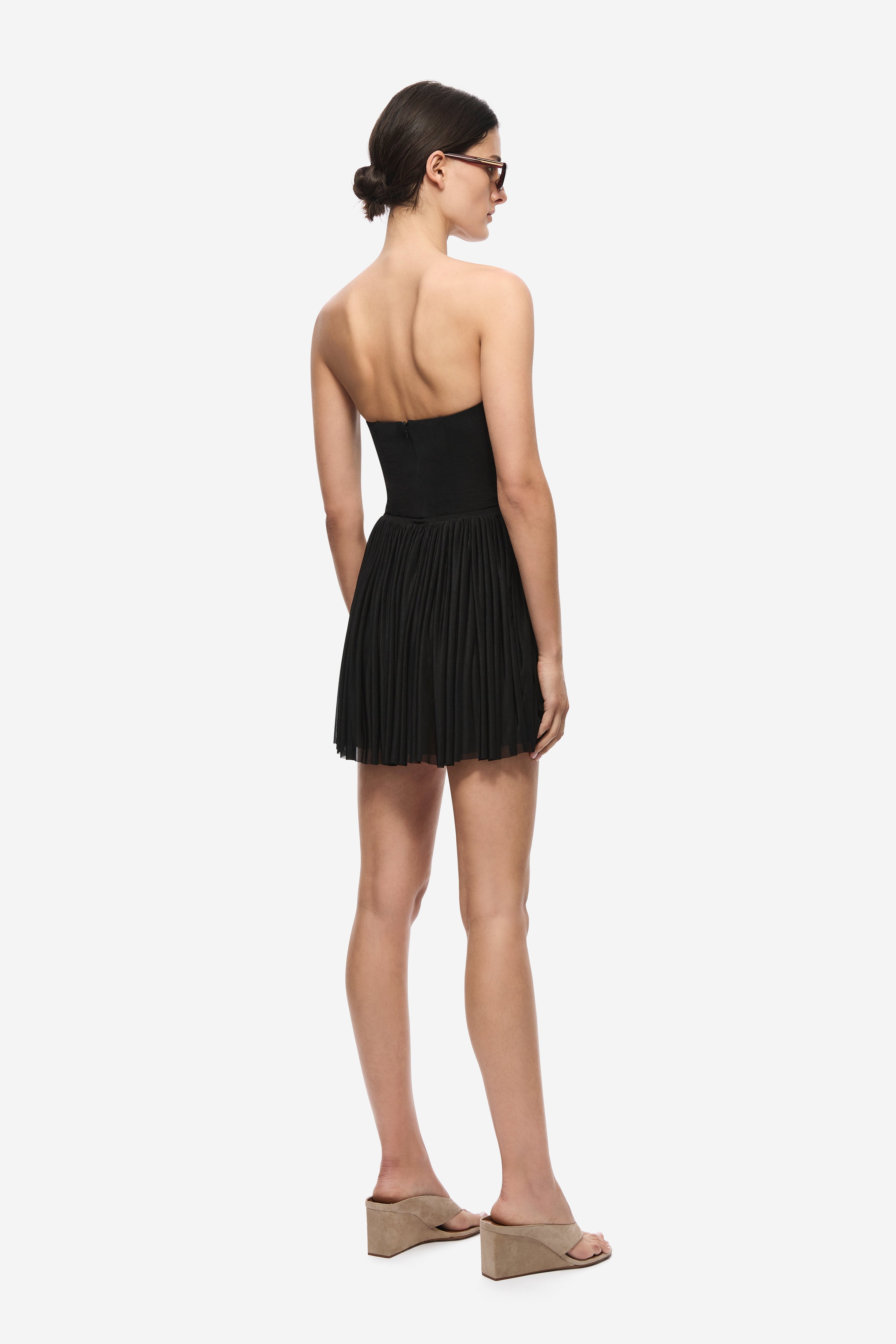 Black gathered jersey mini skirt from back view with elastic waistband pleats.
