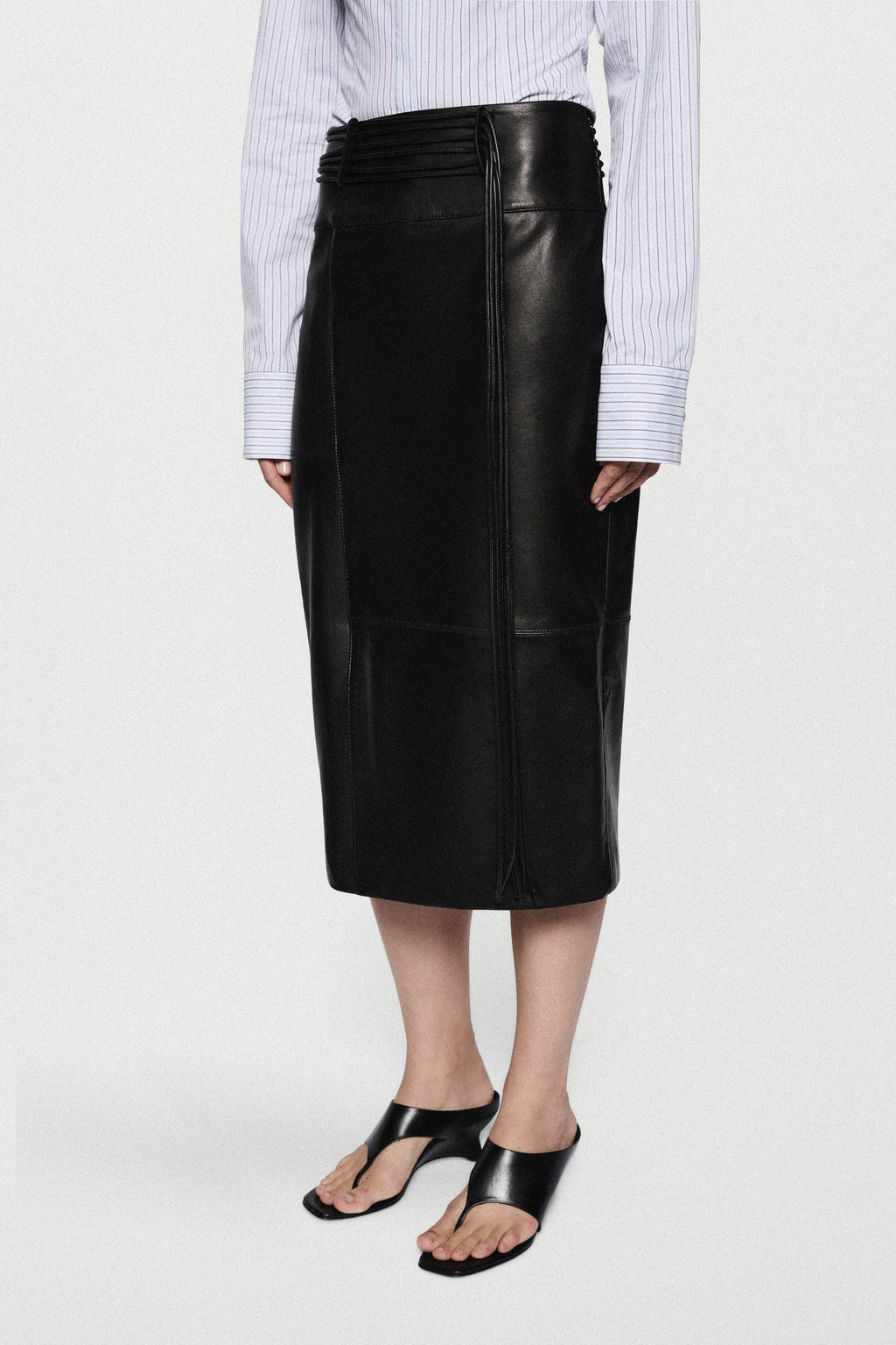 Black leather midi skirt with high waist, center seam, and smooth glossy finish