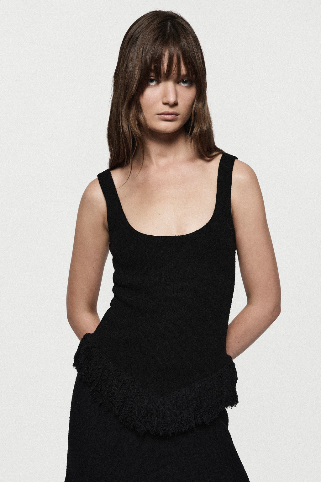 Black sleeveless square-neck top with ruffled fringe detail at lower hem