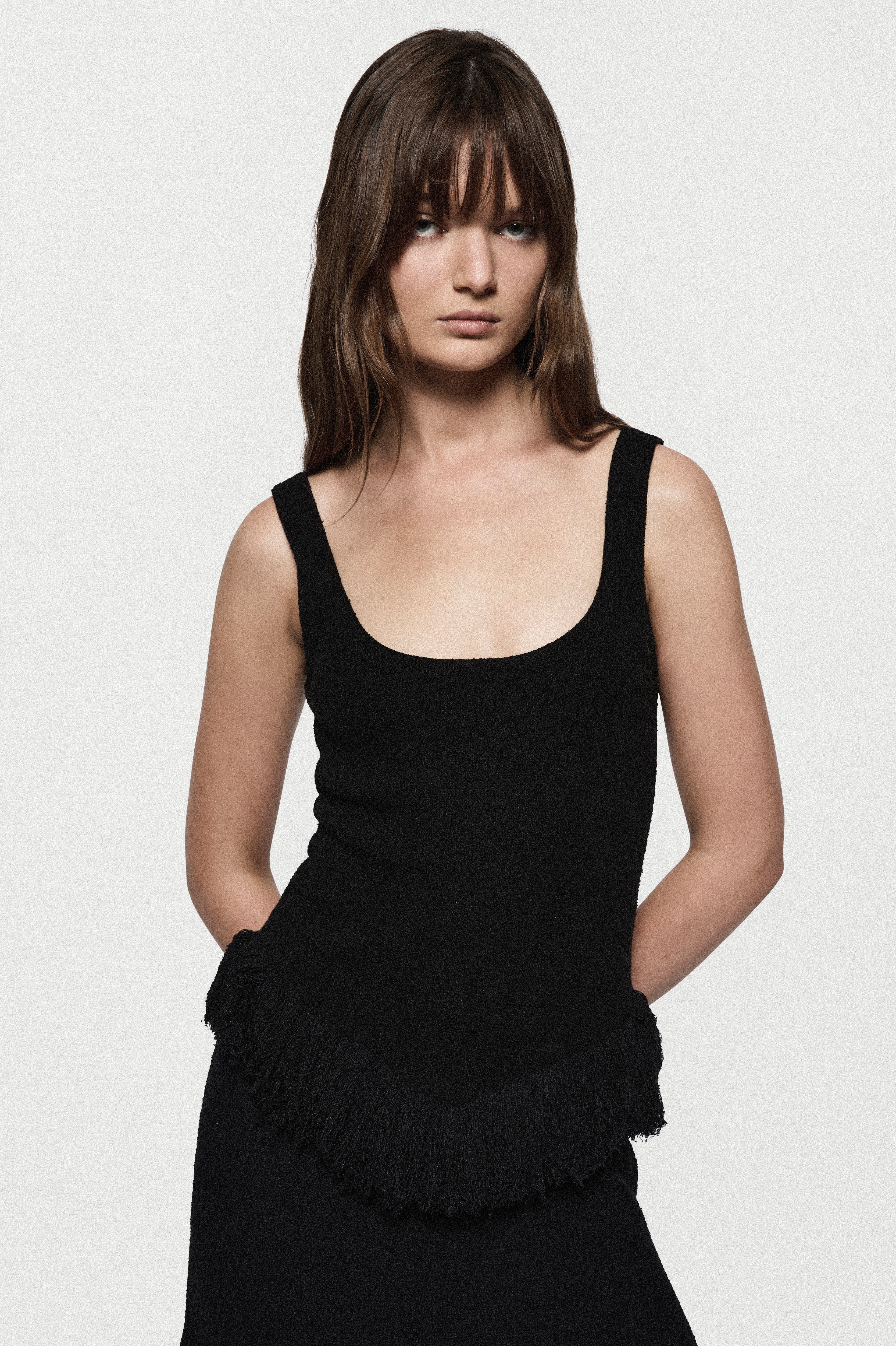 Black sleeveless square-neck top with ruffled fringe detail at lower hem