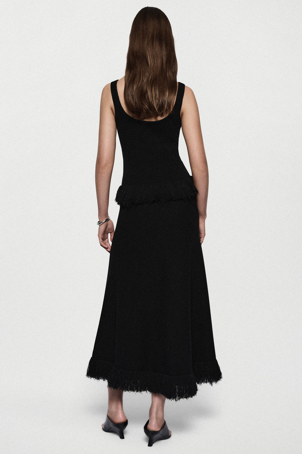 Black sleeveless top with open back and fringe-trimmed hem