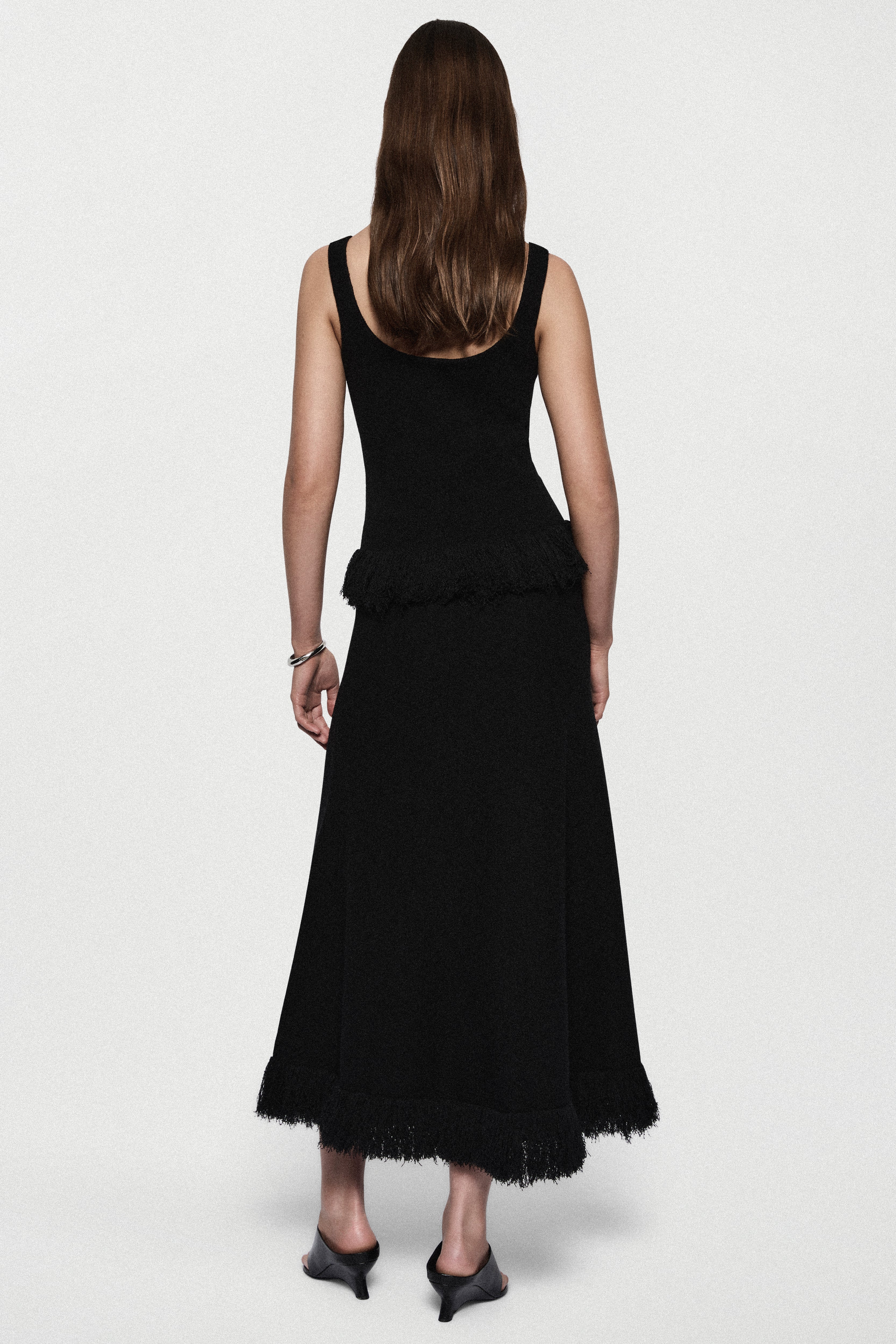 Black sleeveless top with open back and fringe-trimmed hem