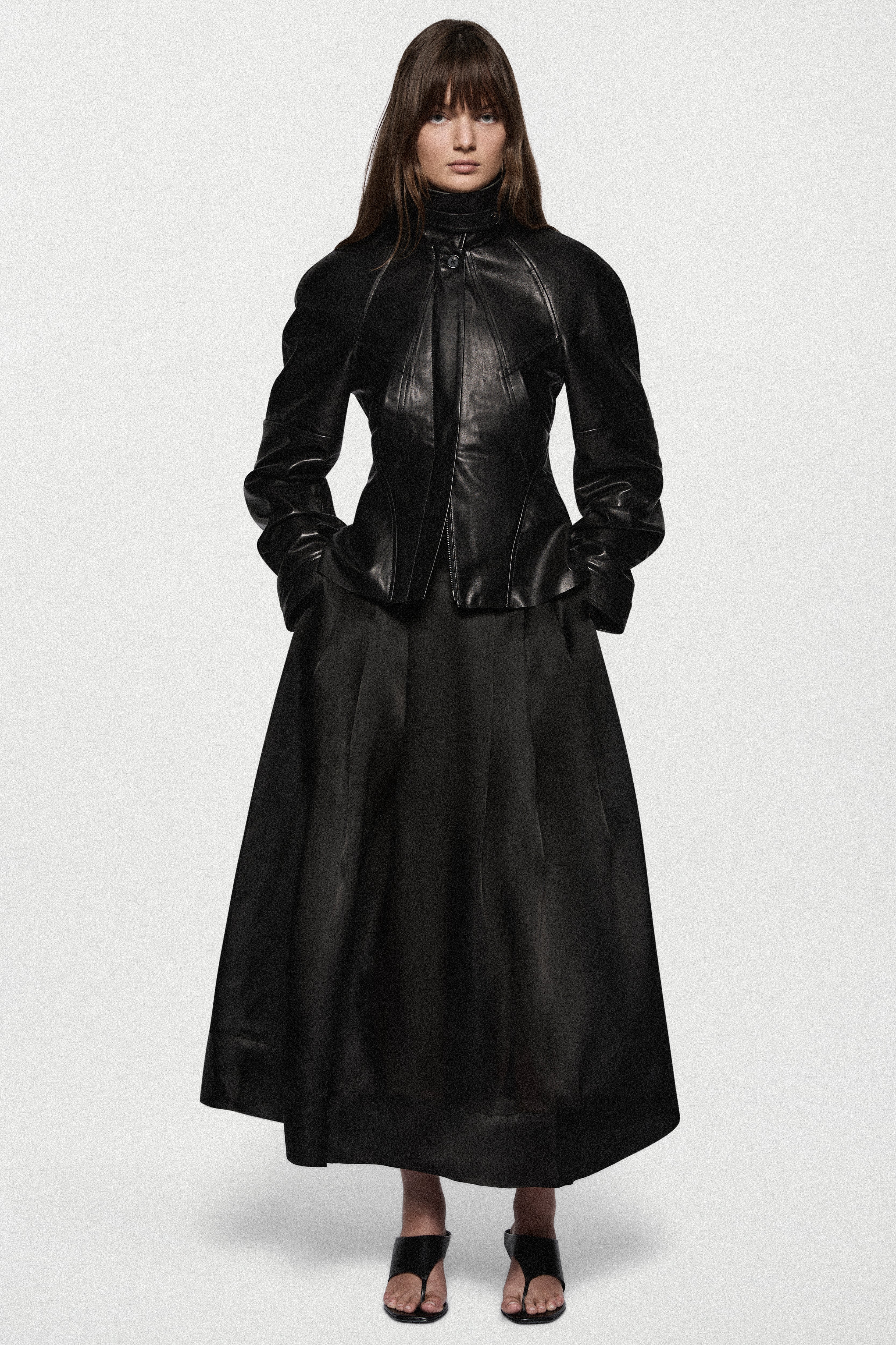 Black leather jacket front view with stand collar, zipper closure, and peplum hem.