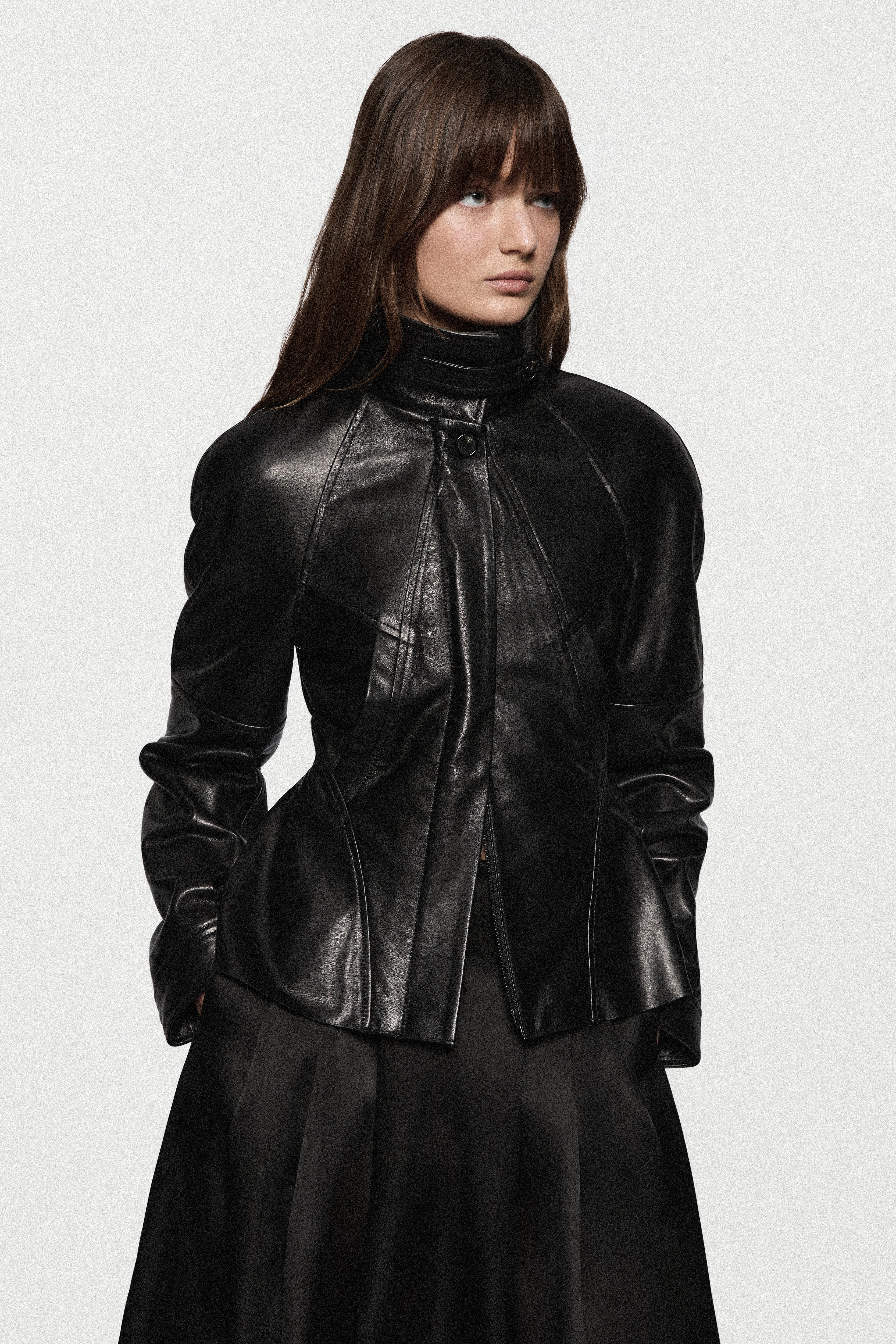 Black leather jacket with stand collar, front zip, and peplum waist detail.