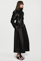 Black leather jacket side view with stand collar, front zip, and flared peplum.