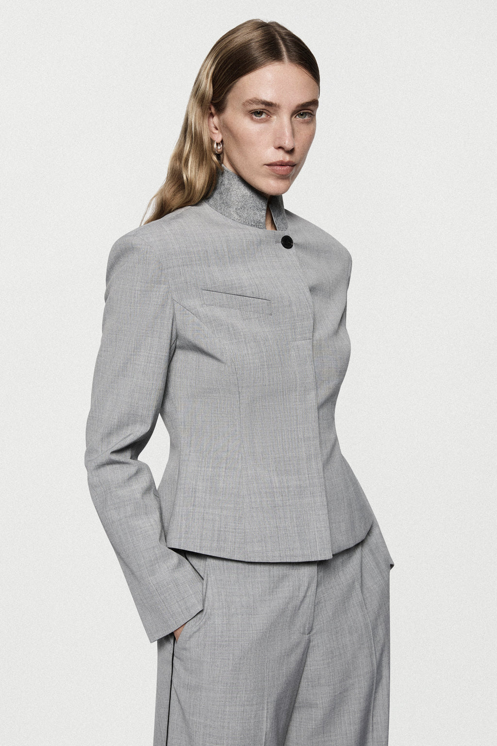 Grey tailored jacket with high neck, button front, long sleeves and fitted waist.