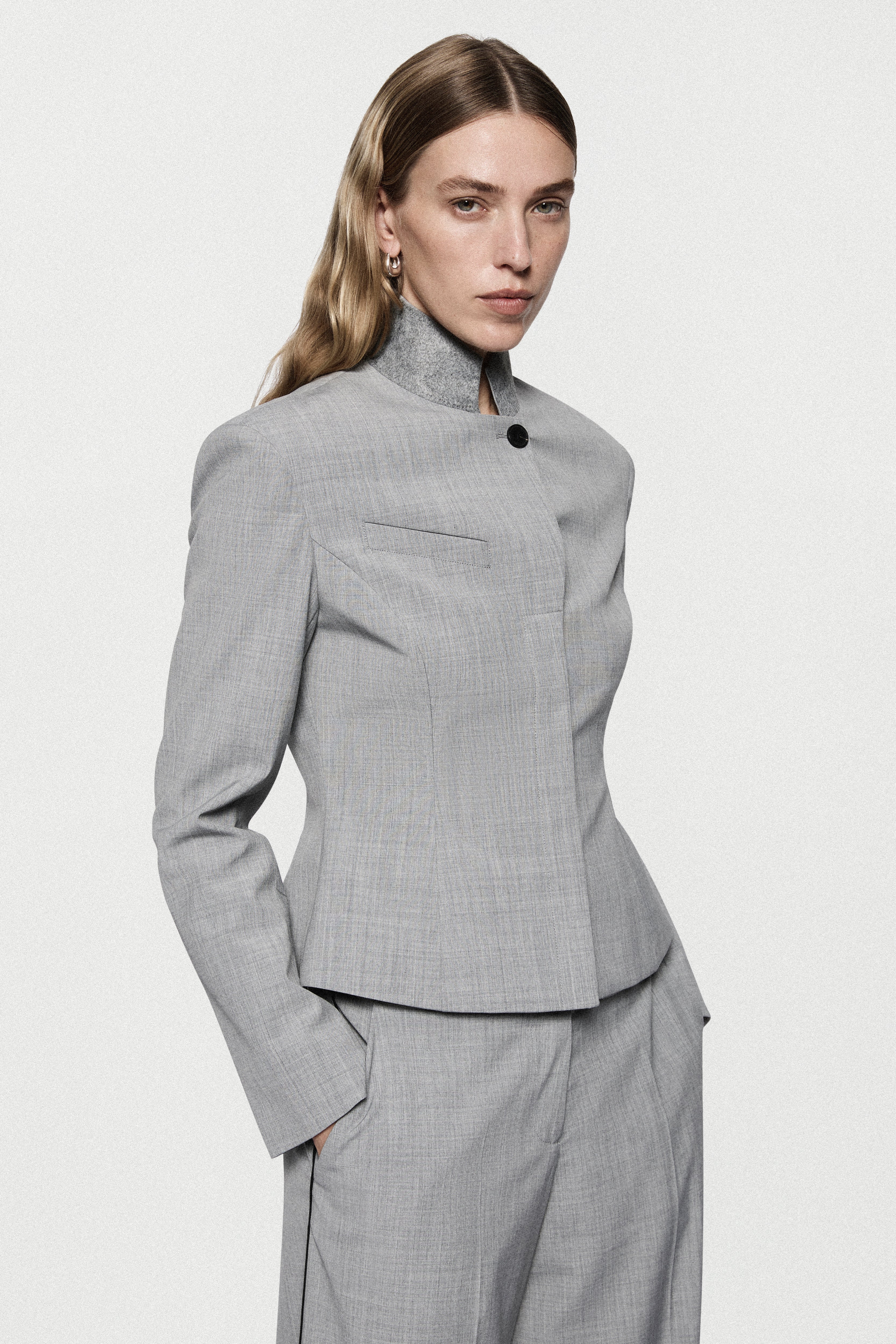 Grey tailored jacket with high neck, button front, long sleeves and fitted waist.