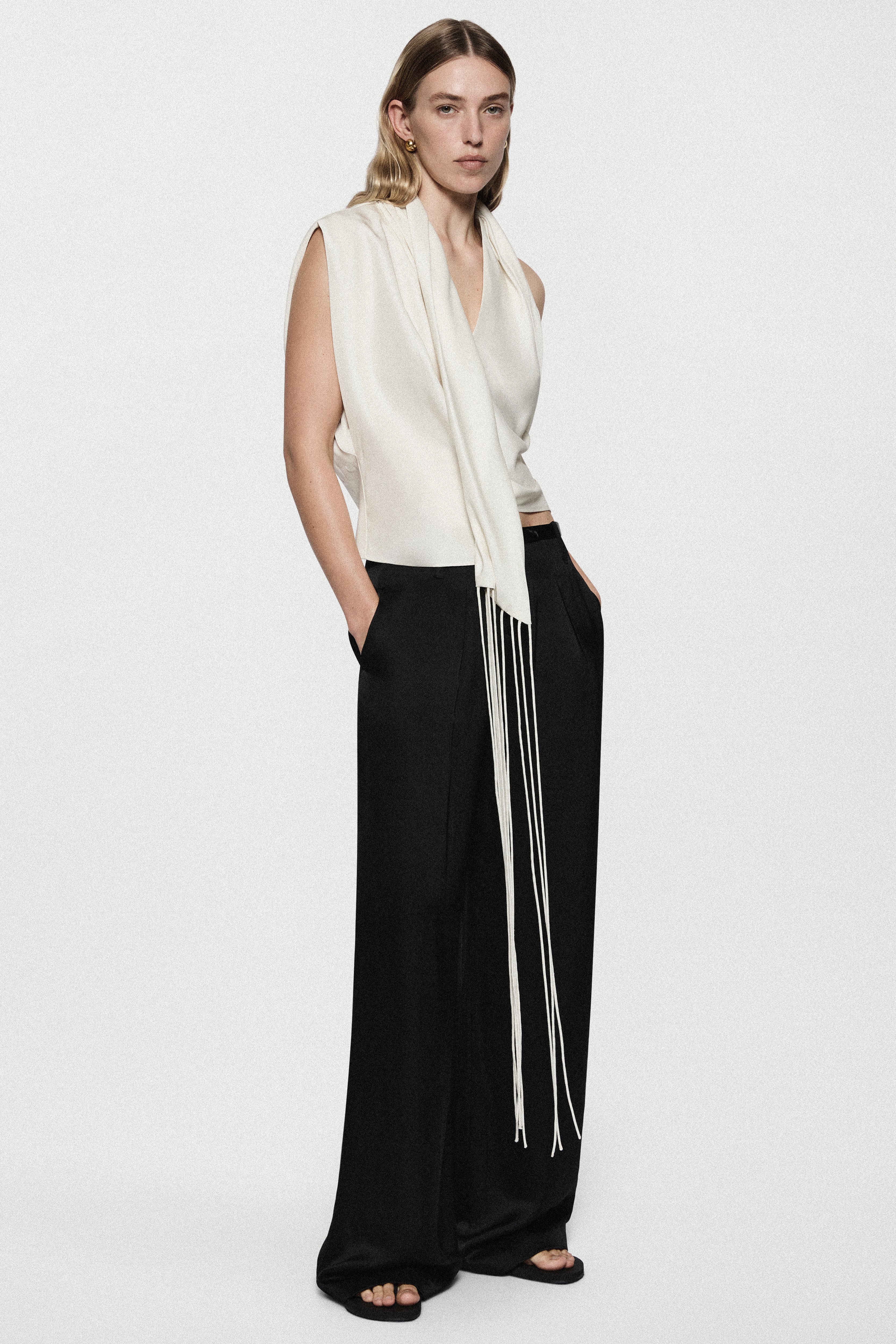 Winter white satin sleeveless top with draped V-neck and long front fringe trim