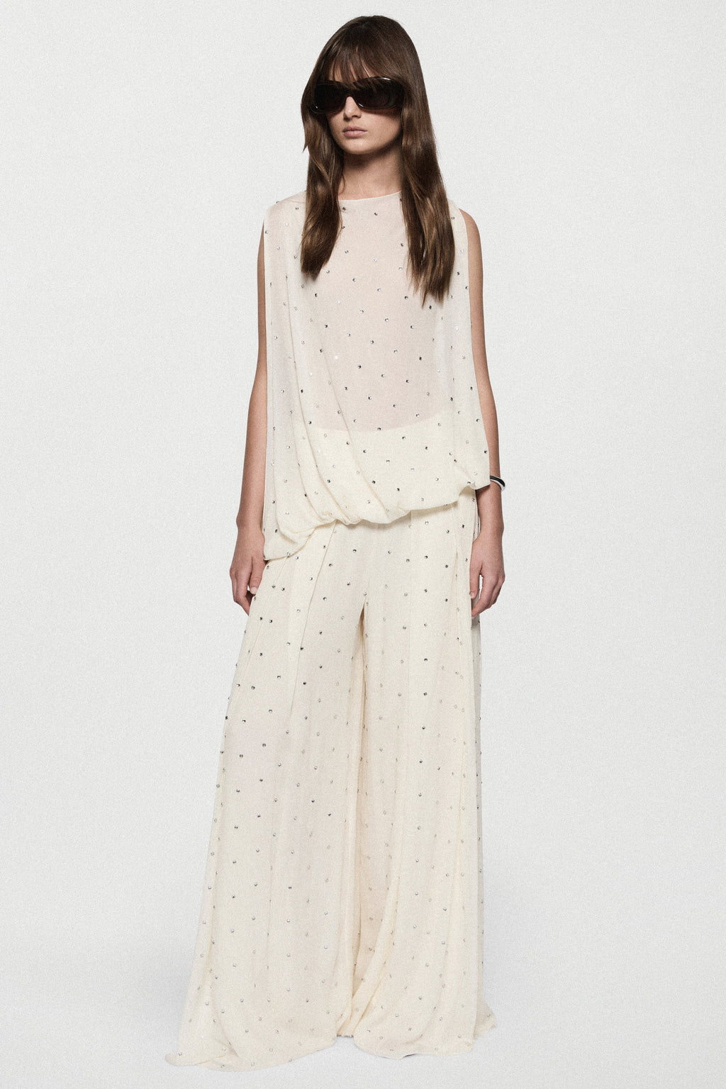 Full-length view of sleeveless winter white rhinestone dot asymmetric top