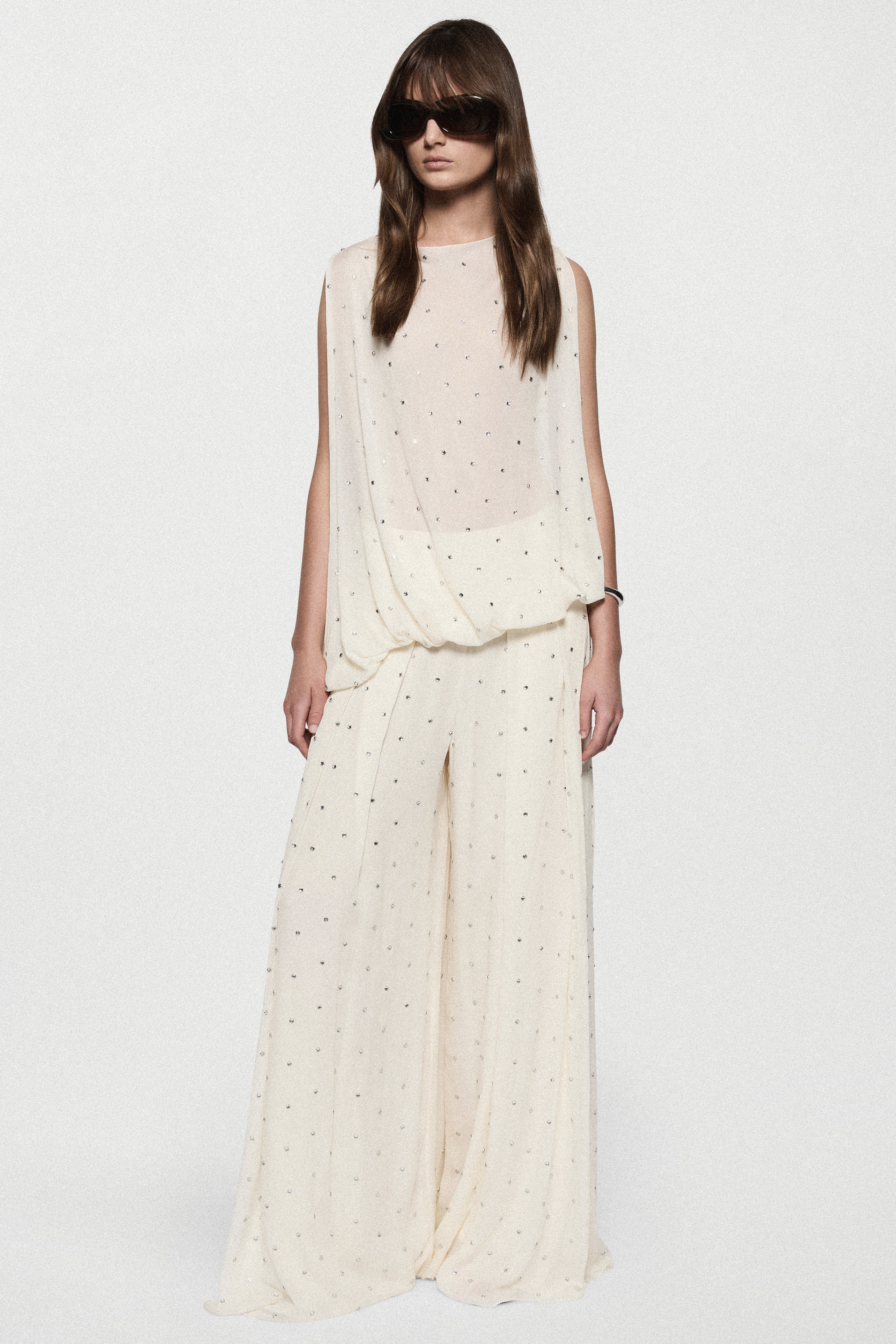 Full-length view of sleeveless winter white rhinestone dot asymmetric top