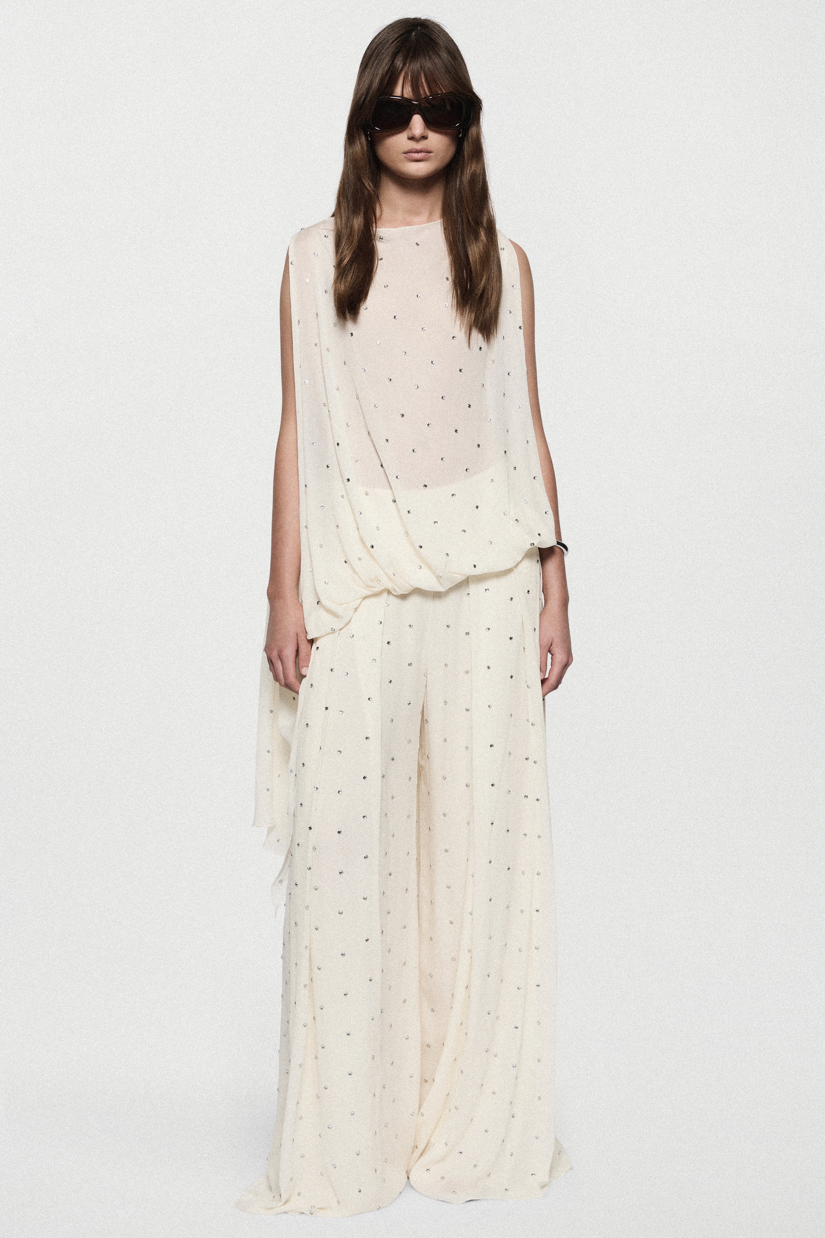 Front view of sleeveless winter white rhinestone dot asymmetric top