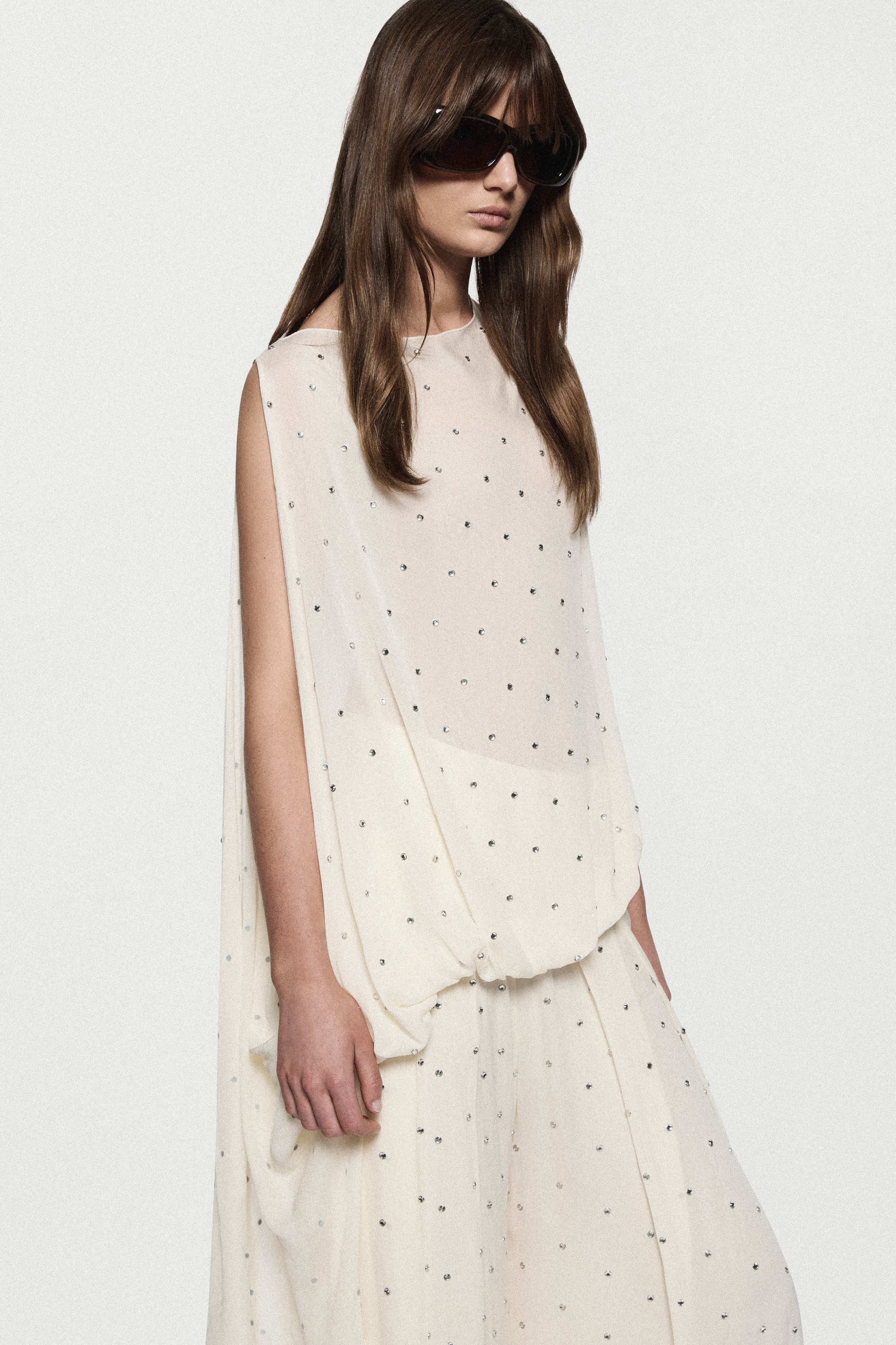 Close-up of winter white sleeveless rhinestone dot asymmetric top