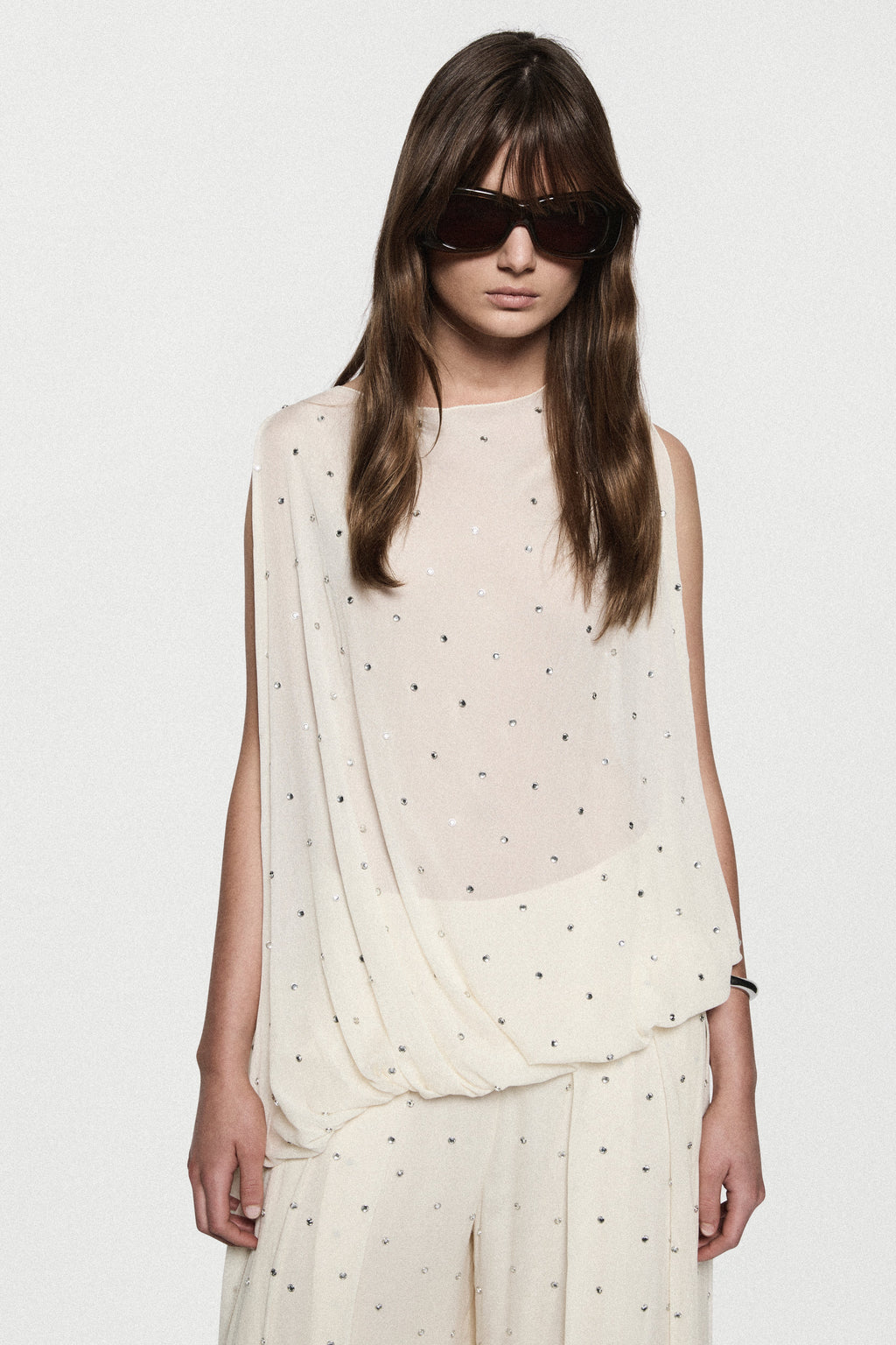 Asymmetric sleeveless rhinestone dot top in winter white with draped front
