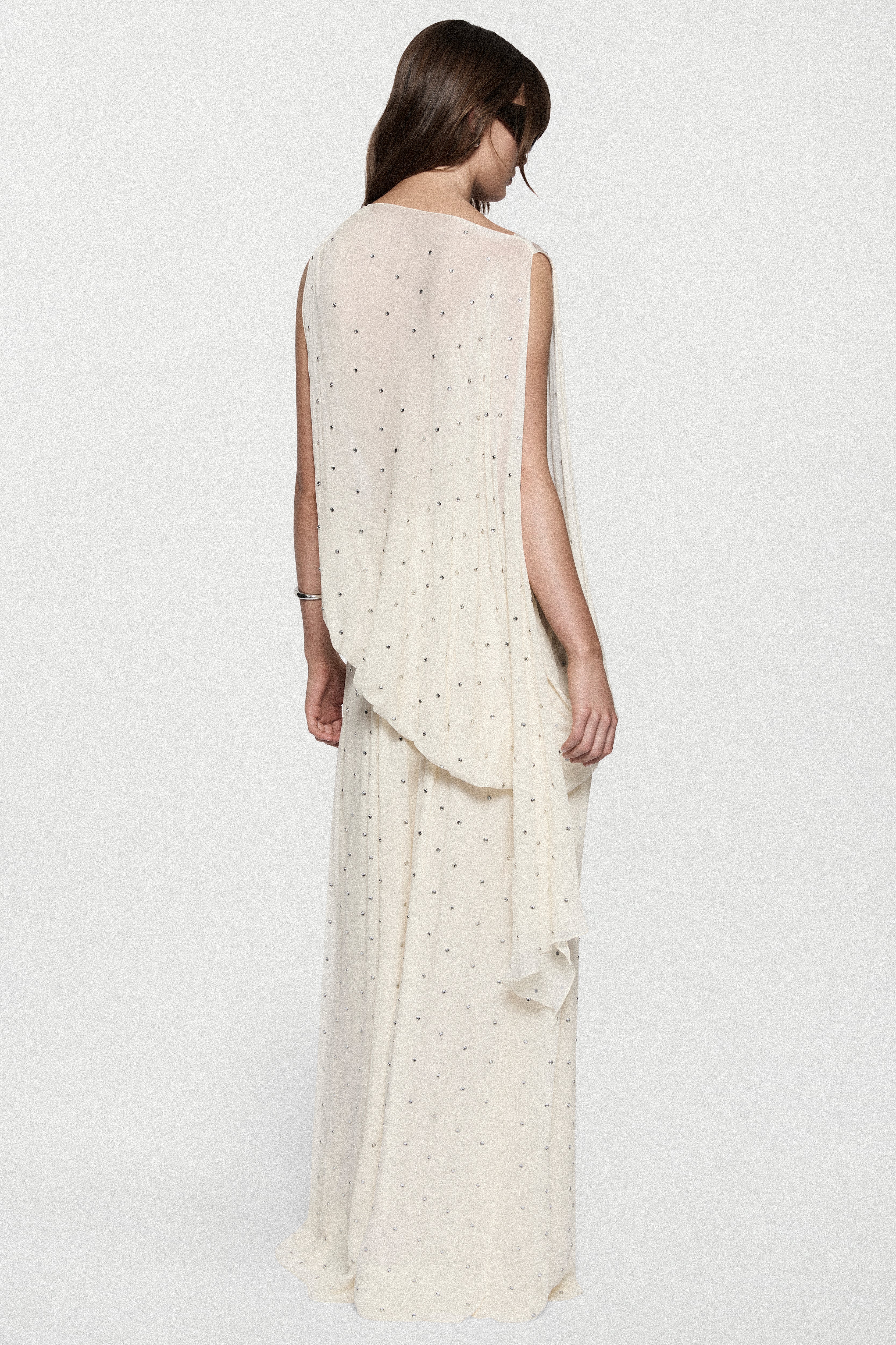 Back view of sleeveless winter white rhinestone dot asymmetric top with drape