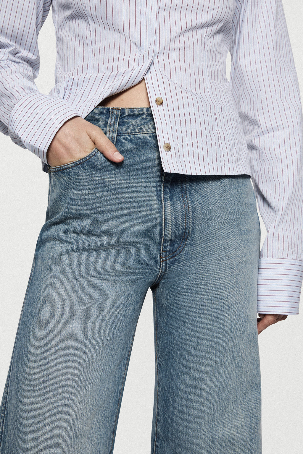 High-rise vintage wash jeans close-up: faded denim waist with button and zip