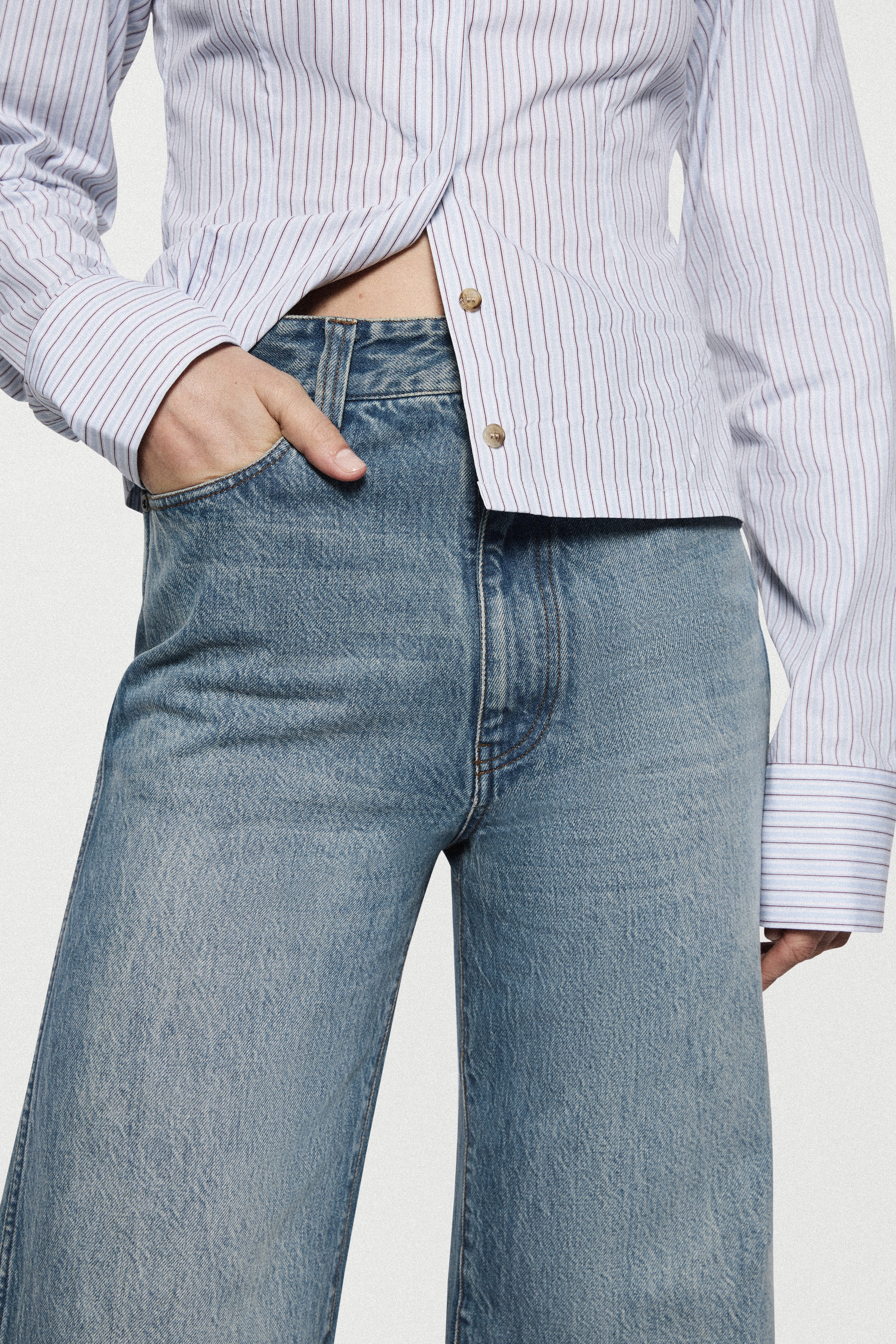 High-rise vintage wash jeans close-up: faded denim waist with button and zip
