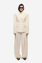 Cream blazer with notched lapels, two-button front, and flap pockets.