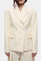 Cream blazer close-up with notched lapels, gold-tone buttons, and flap pockets.