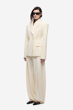 Cream blazer with notched lapels, two-button front, and flap pockets.