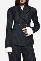Charcoal pinstripe wool blazer close-up with button front, long sleeves, and flap pockets.