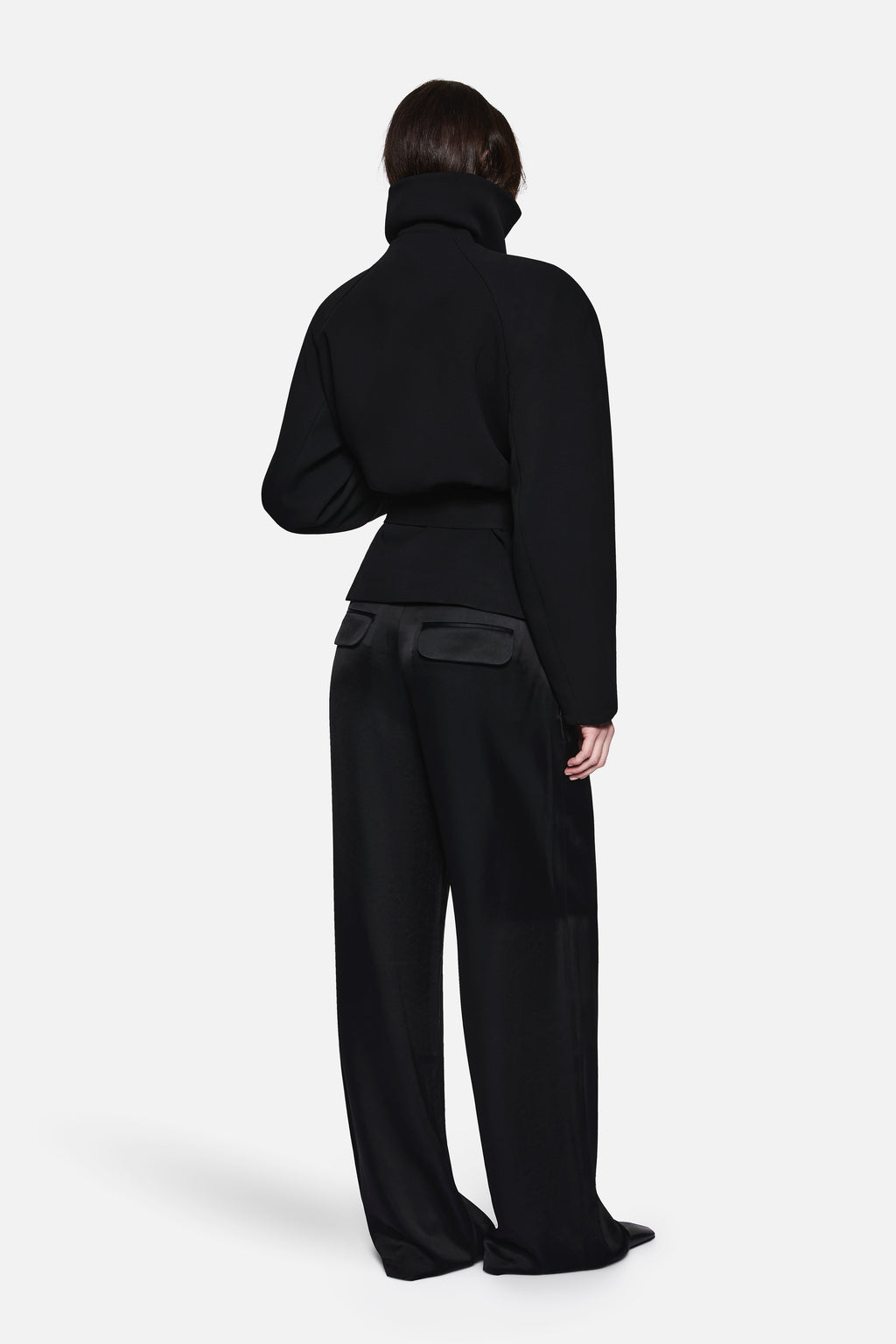 Black back view of acetate collared jacket with stand collar and belted waist.